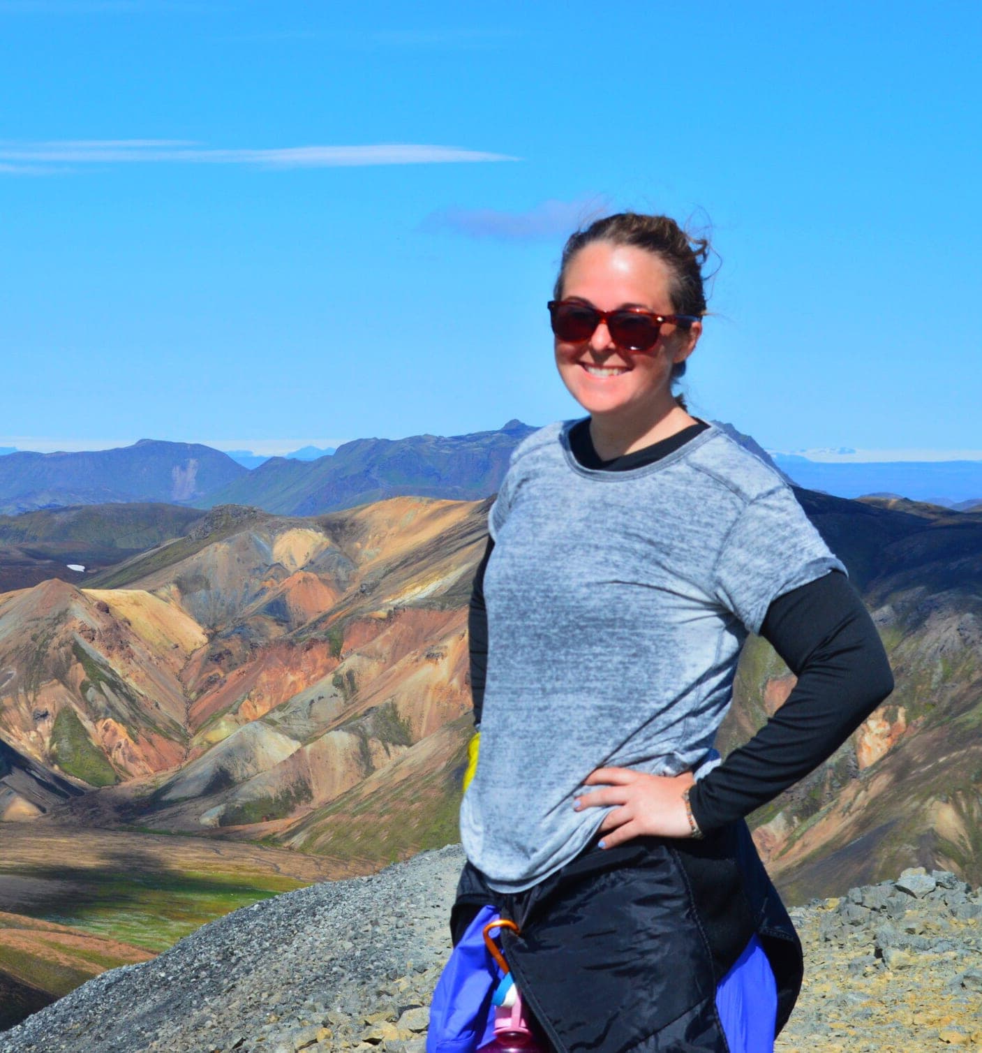 Advisor smiling with her hand on her hip while on hike with a beautiful mountain range behind her