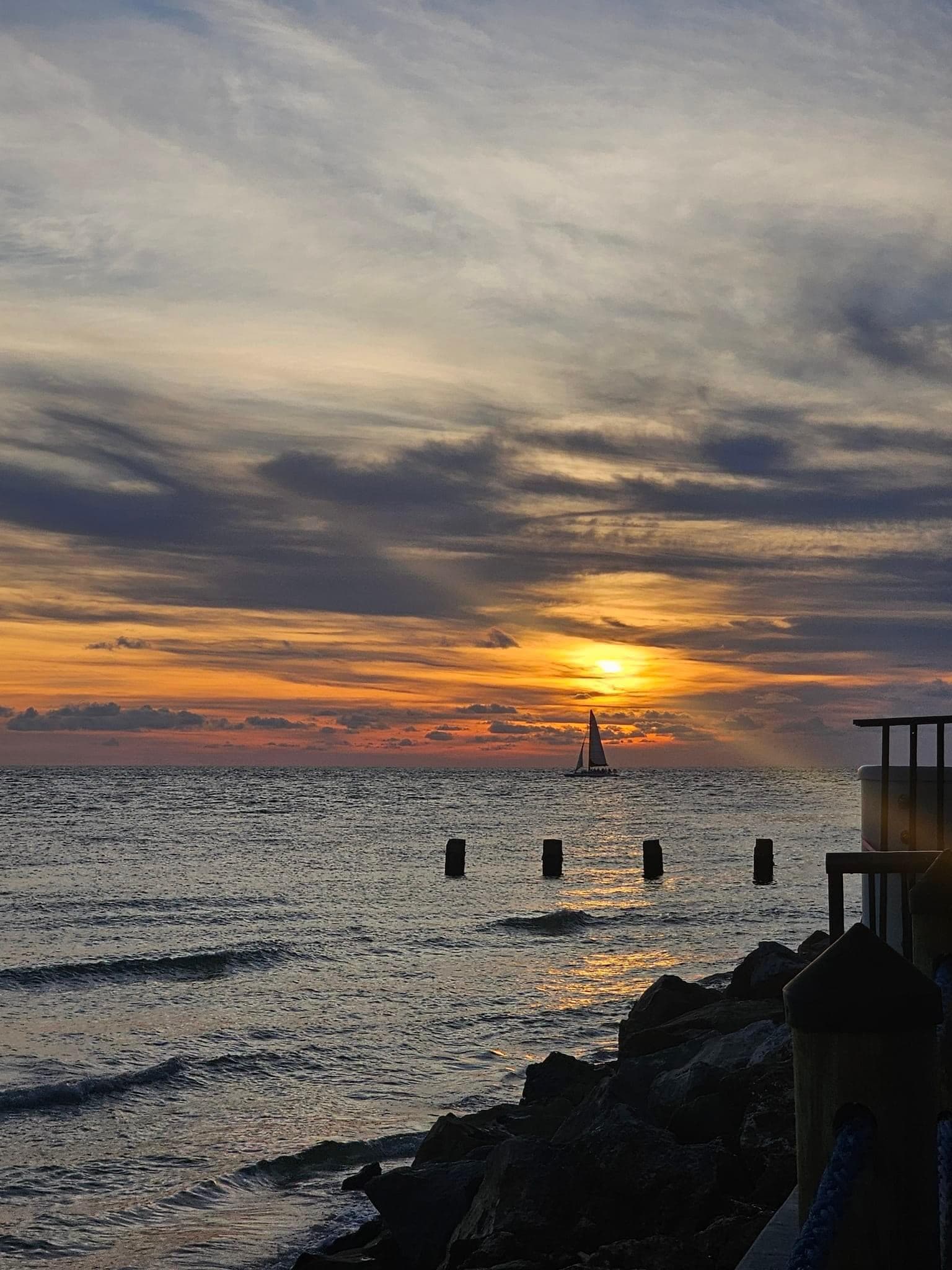 View of an orange sunset peeking through the clouds over the sea