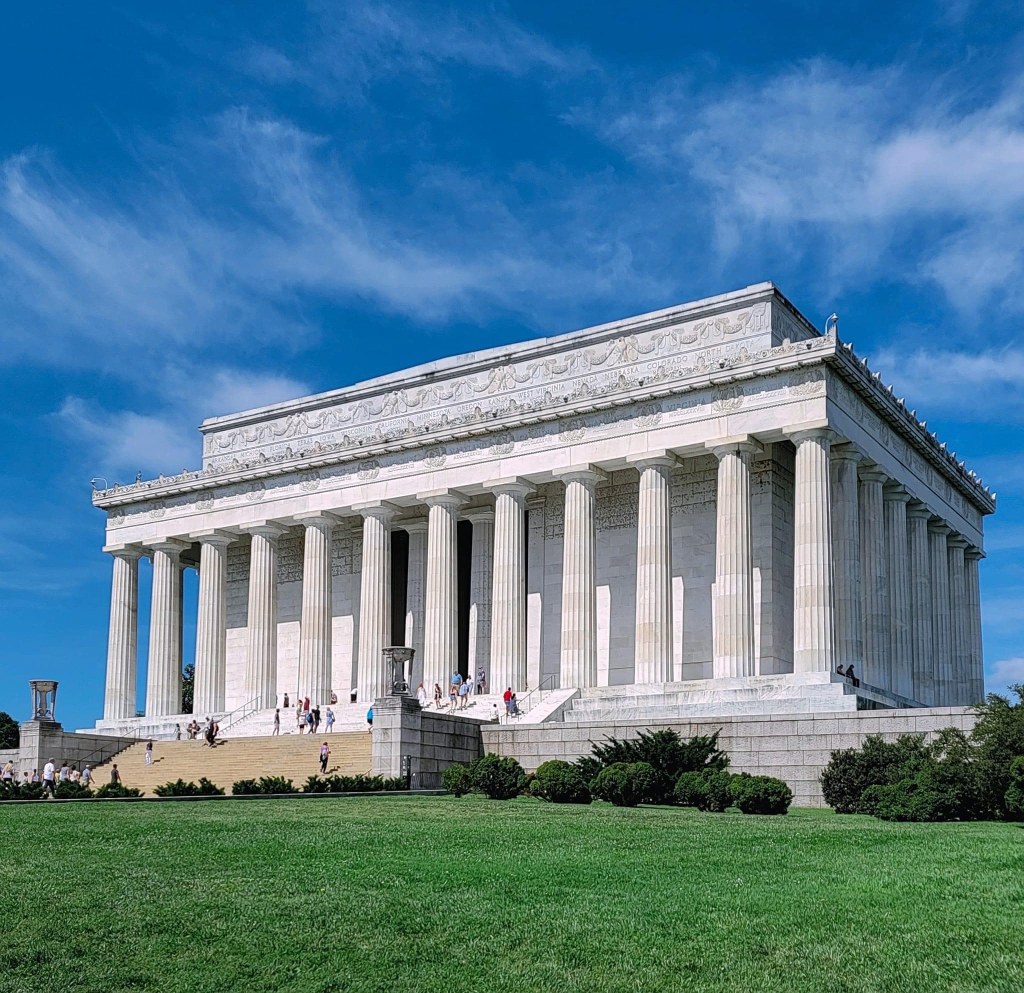 View of a white building with large columns and a grassy area in front