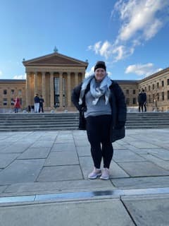 Debbie posing in front of a monumental building during the daytime.