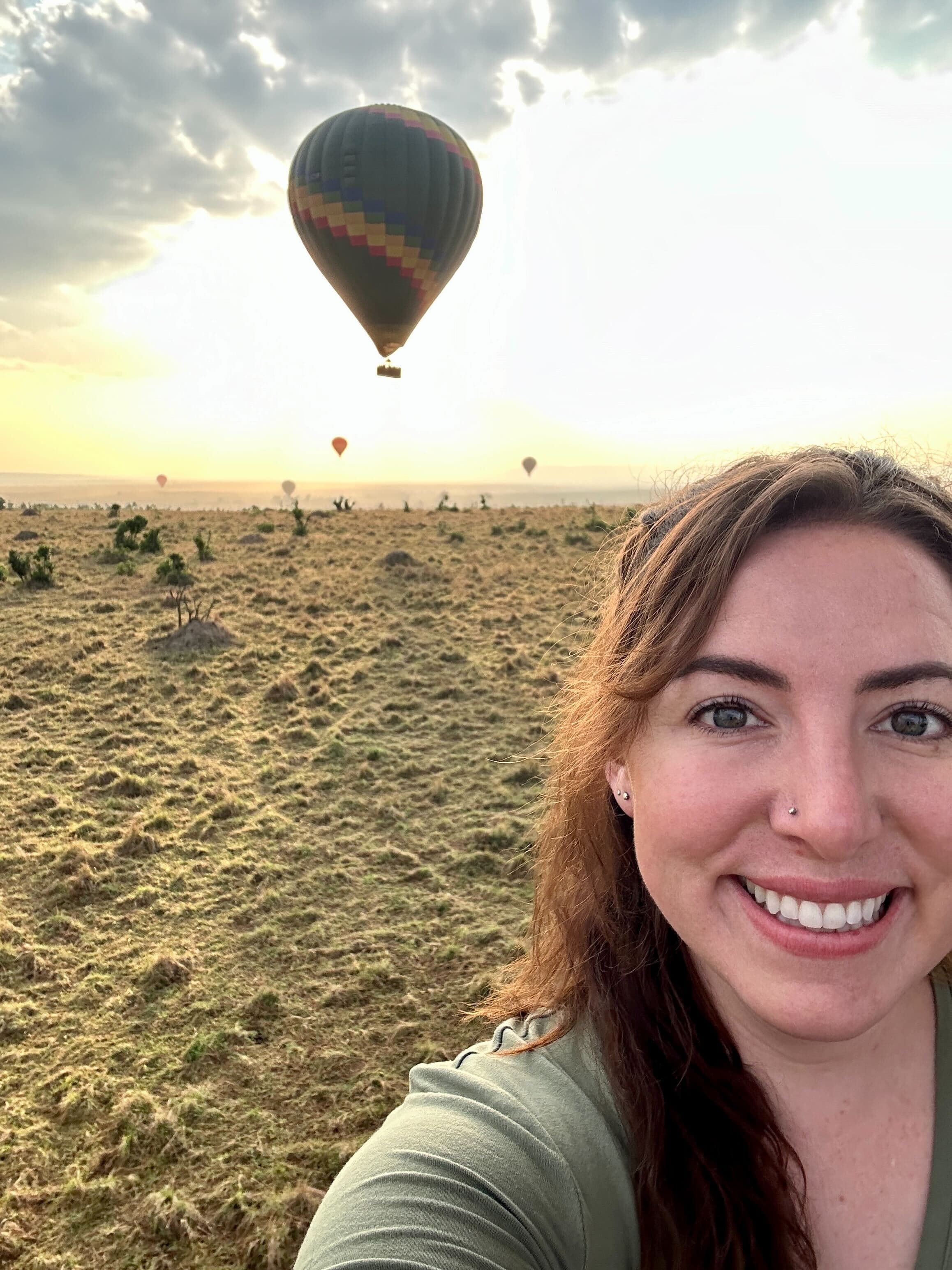 Advisor taking a selfie at sunset with a hot air balloon in flight behind her