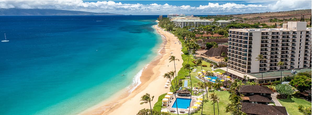 Aerial view of a long sandy beach lined with resort buildings