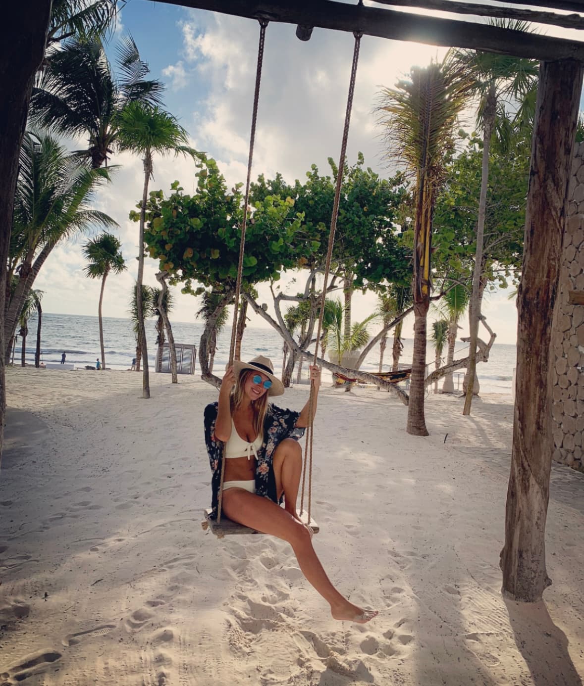 Meagan posing on a swing on the beach during the daytime.