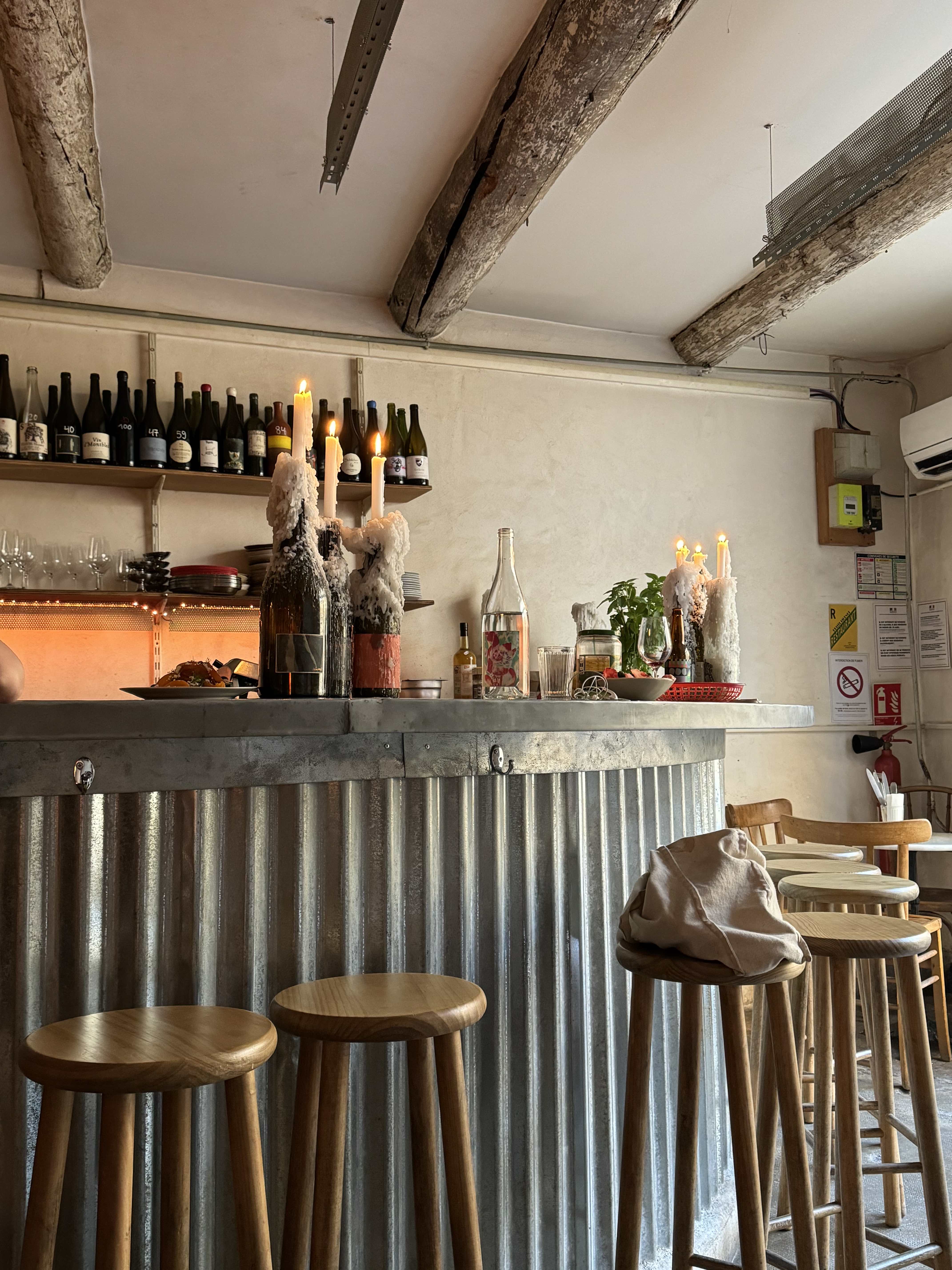 View of empty stools at a bar with wine bottles on the shelf behind it
