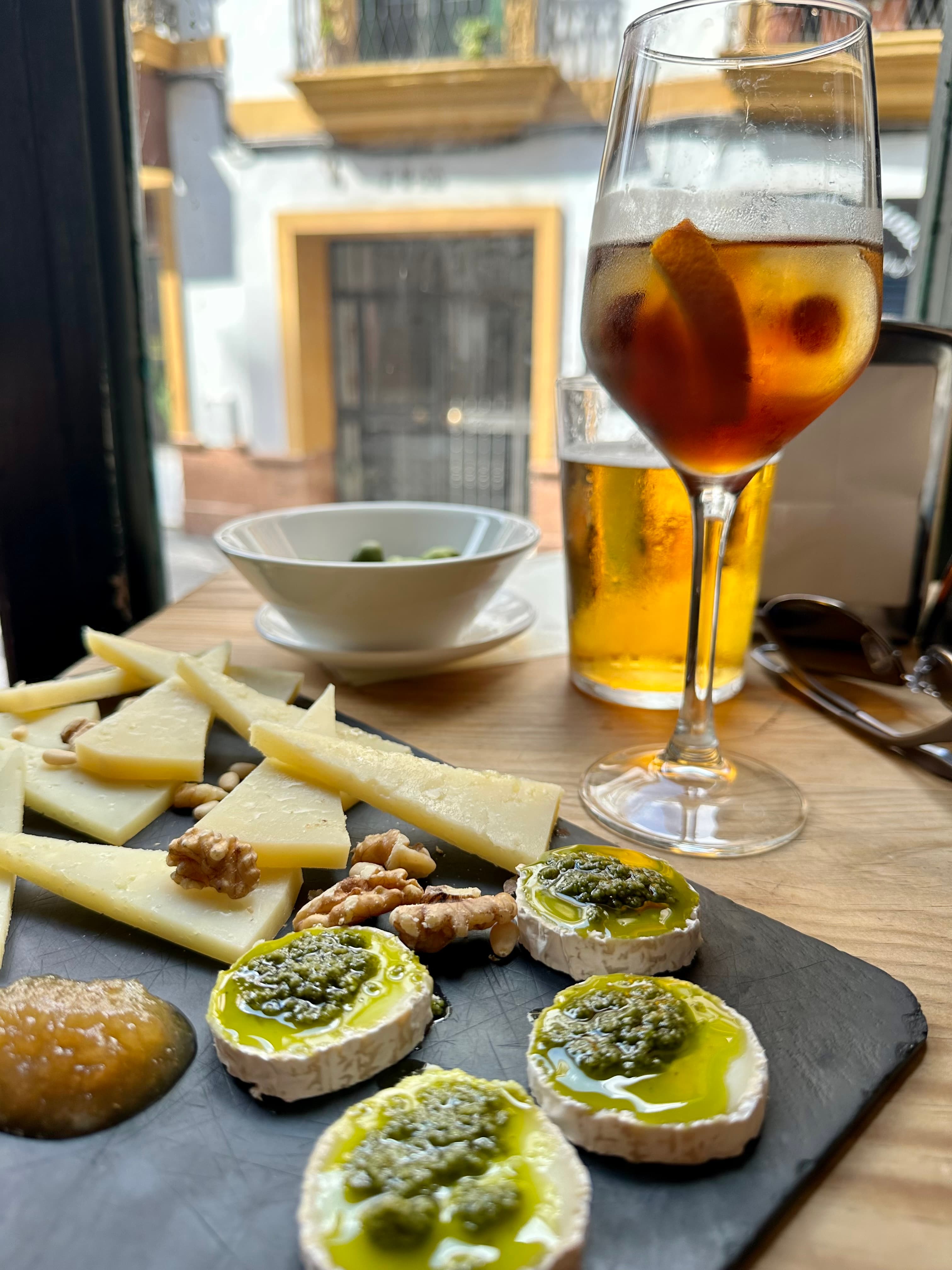A view of a drink and snacks on a platter for aperitivo.