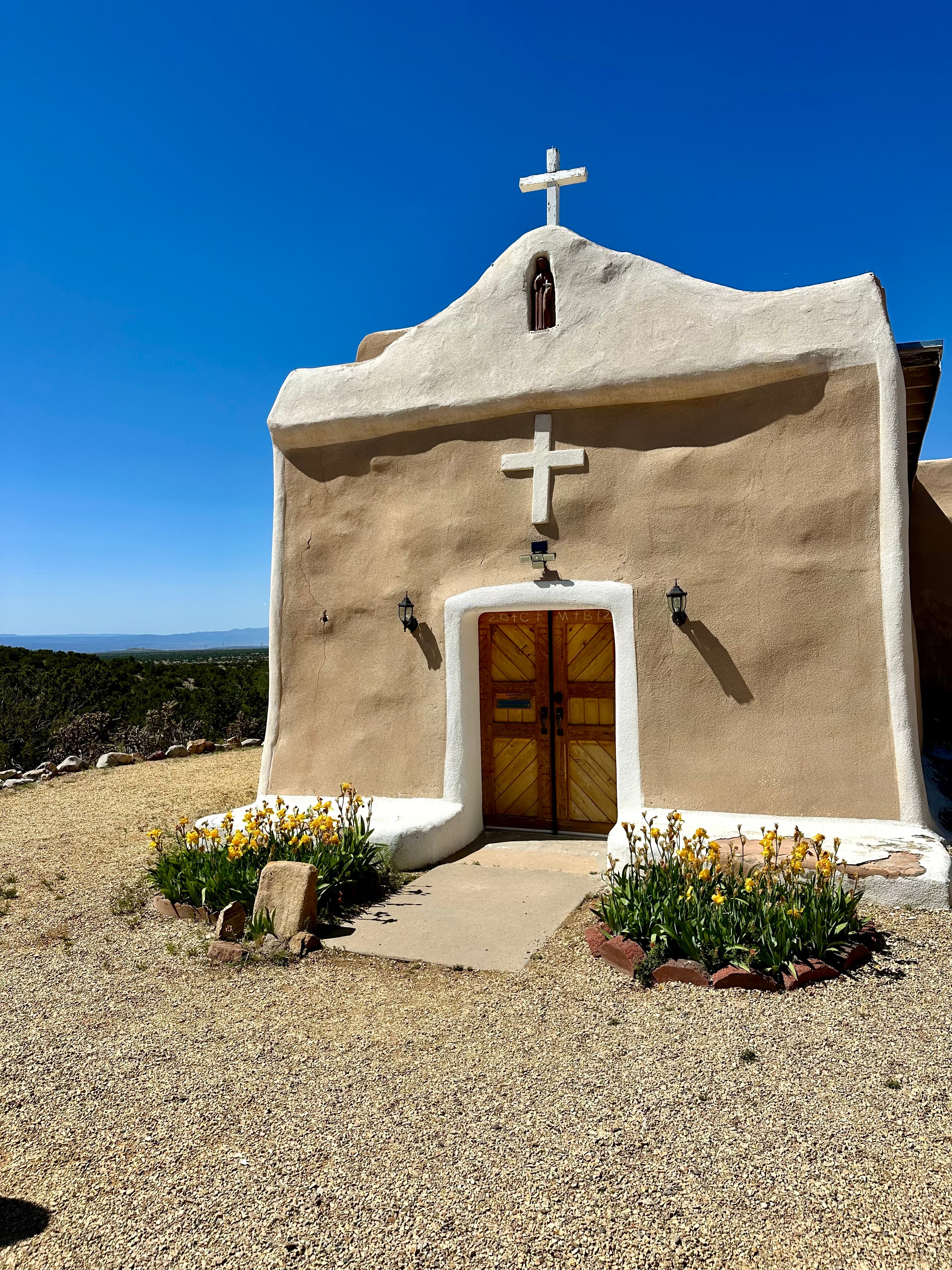 A stone church with bushes and a vibrant blue sky in the background.