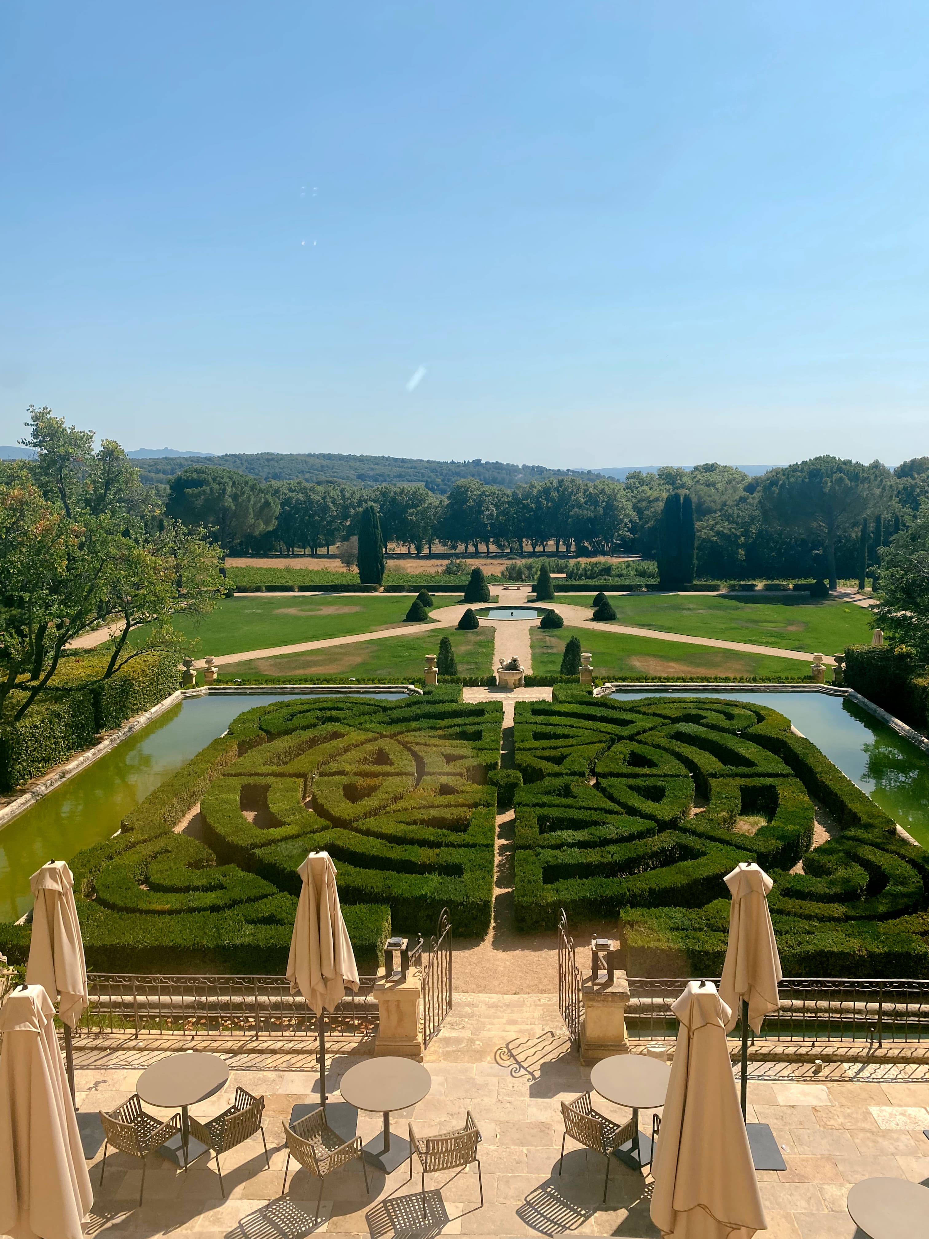 View of manicured gardens with a maze and surrounding ponds on a clear day