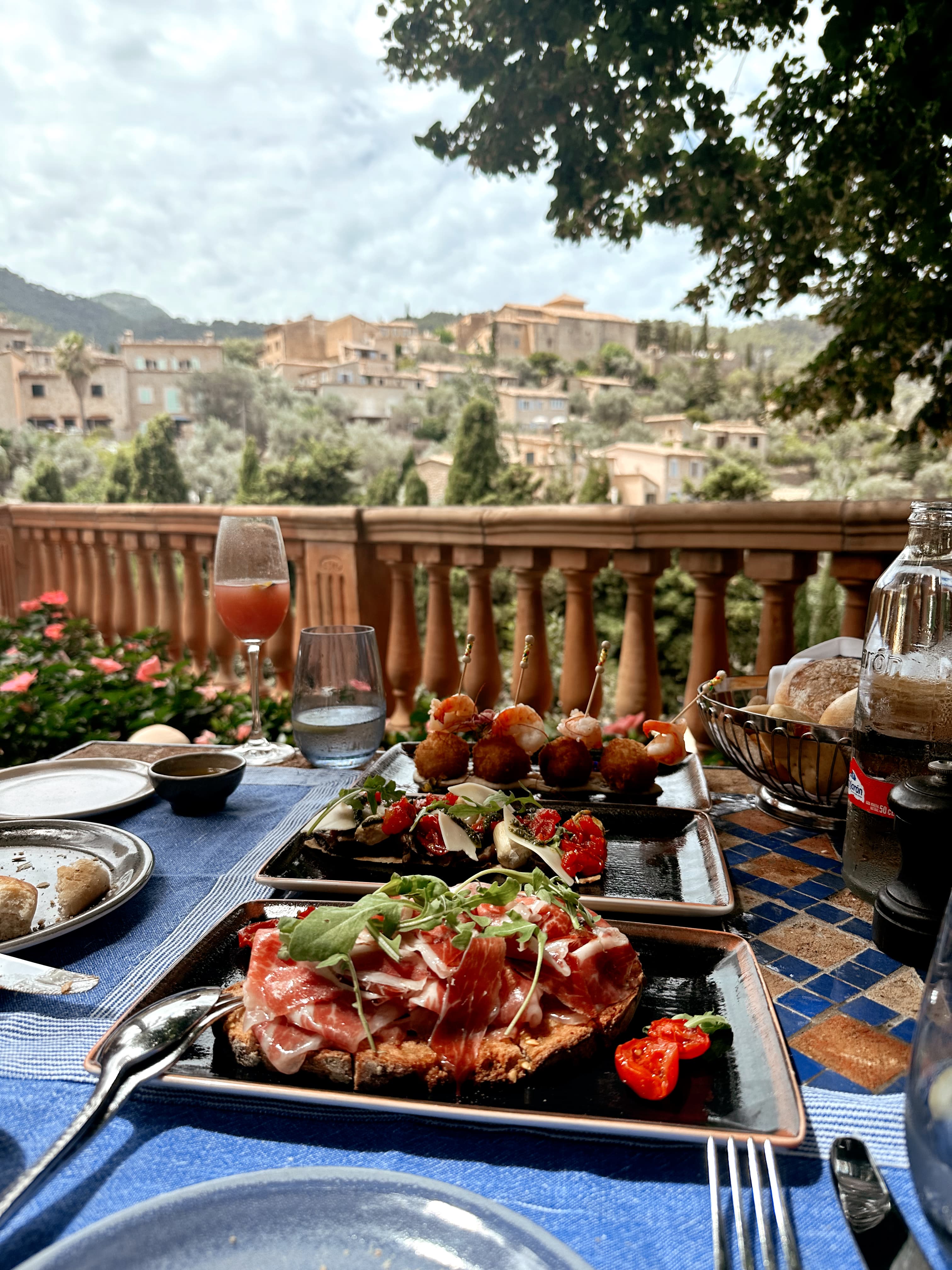 View of artfully plated food on a square black dish outdoors on a table overlooking a sunny valley