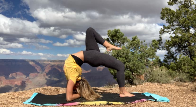 Advisor in a back bend yoga pose at a viewpoint overlooking a canyon