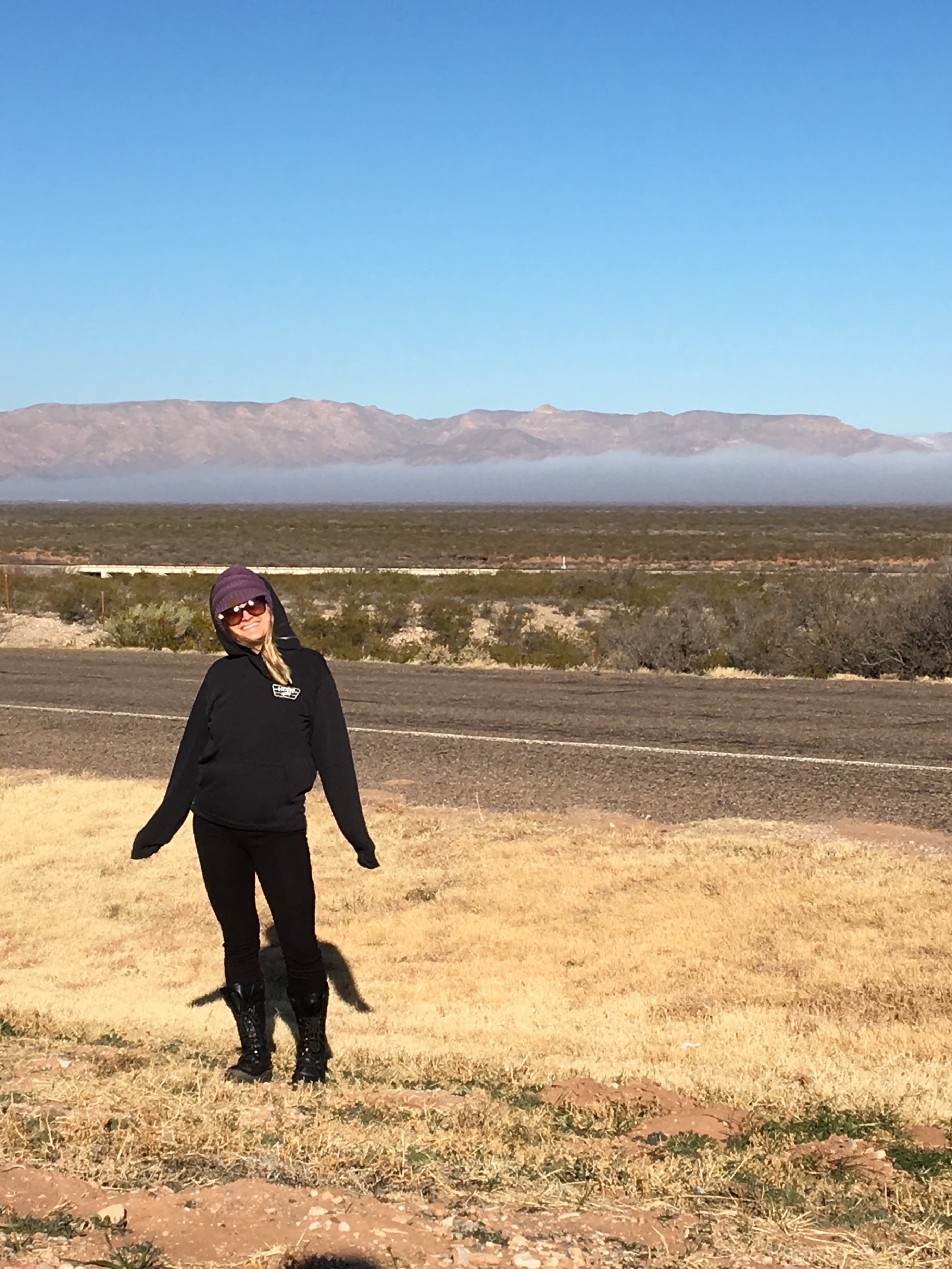 Advisor posing on the side of a street with a vast flat plain stretching out behind her on a sunny day