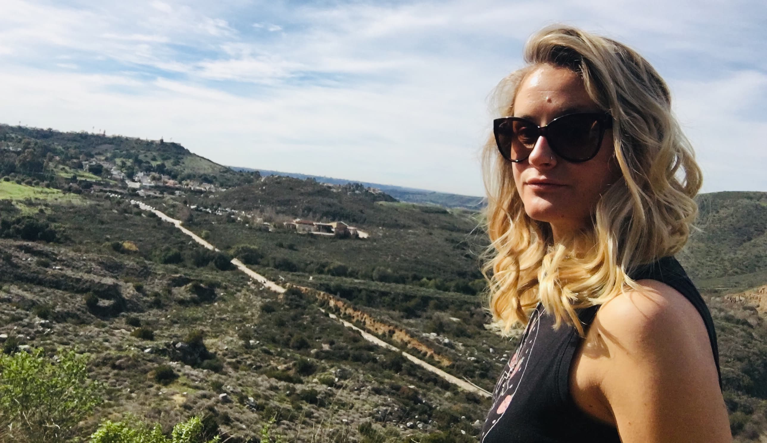 Advisor in big black sunglasses on a hike through green mountains on a sunny day