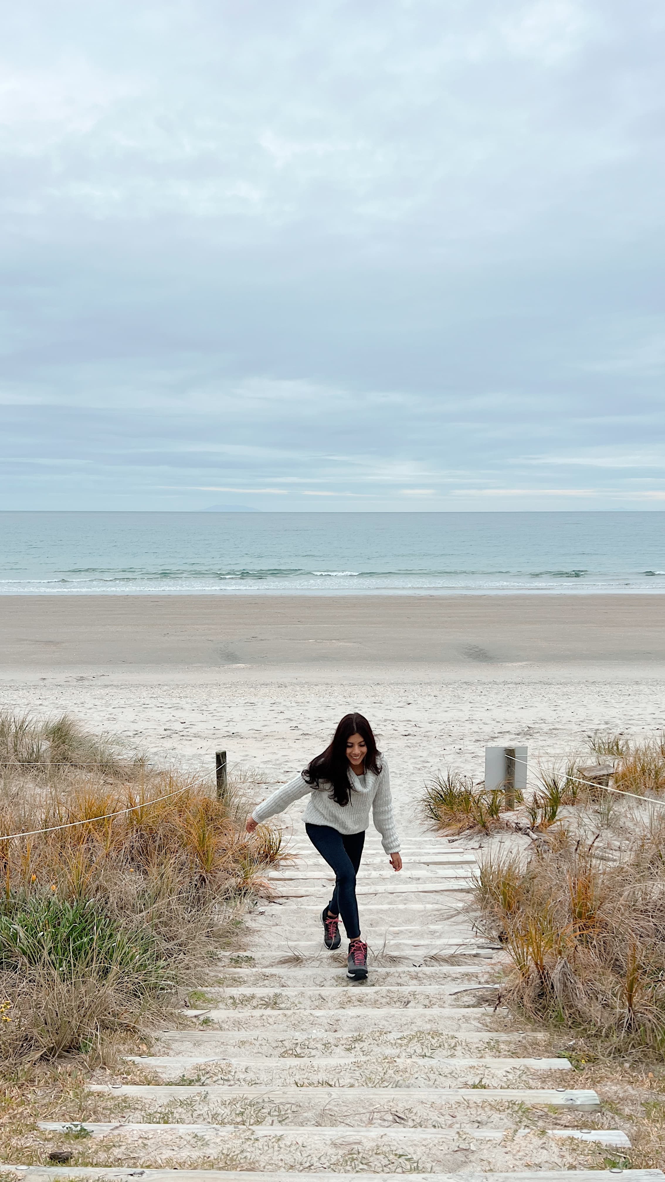 Advisor walking up sandy steps away from the beach on a cloudy day