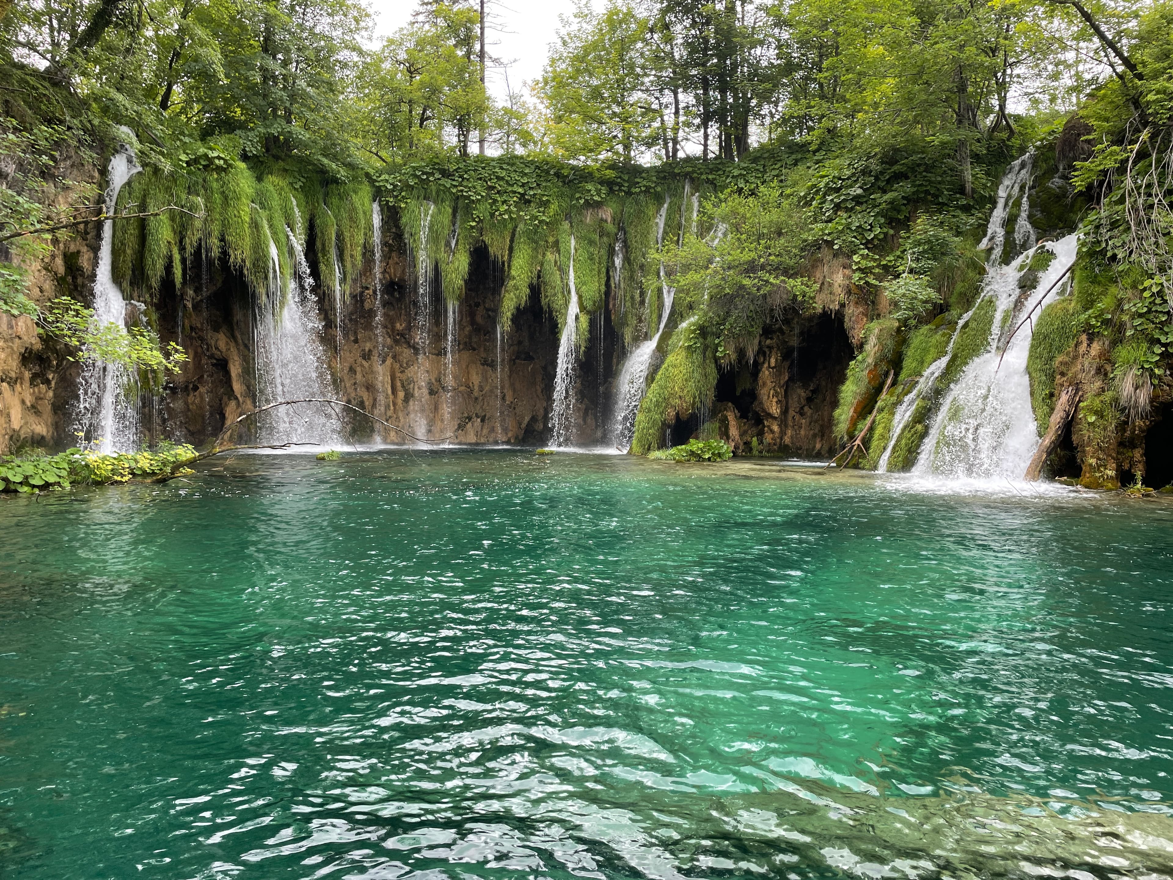 View of a waterfall with green tinted water in nature during the daytime.