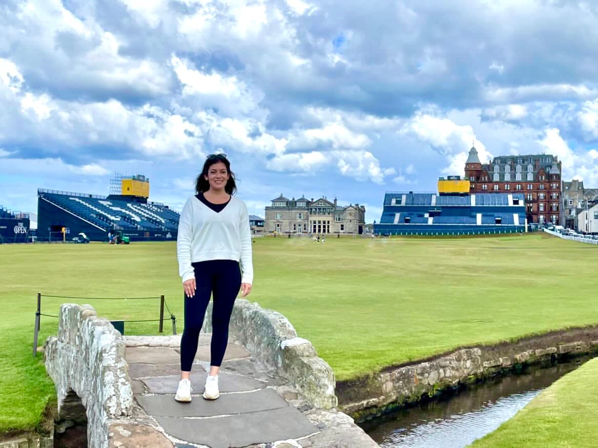 Jessica posing on a bridge outdoors with buildings in the background during the daytime.