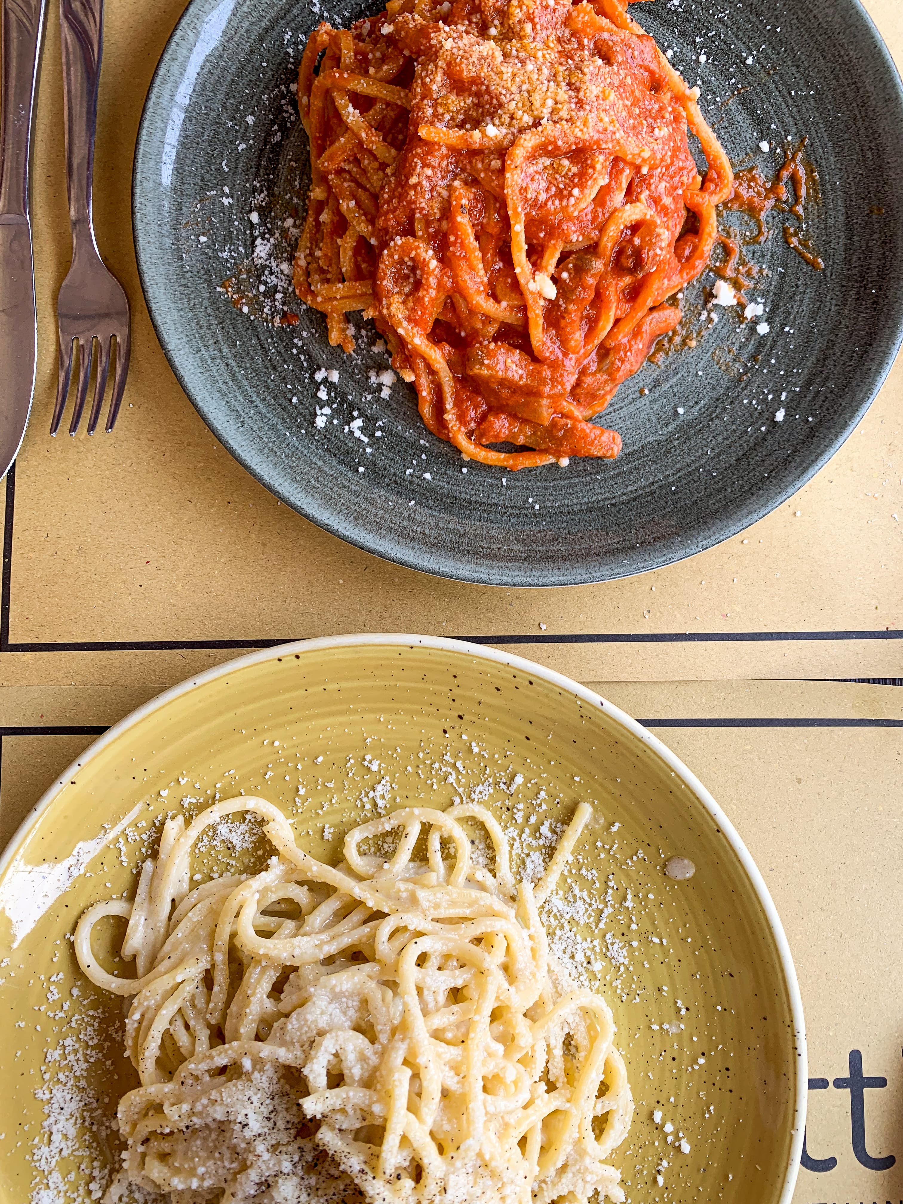 Two plates on a table with pasta on each.