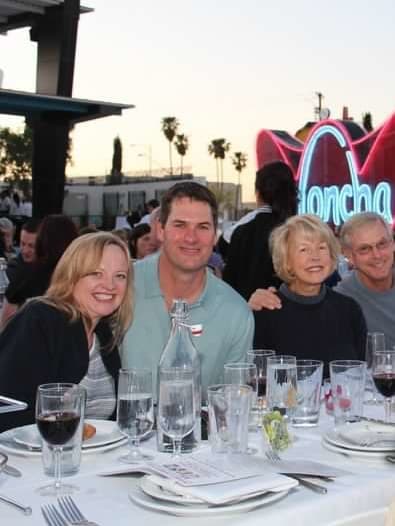 View of four people smiling around an outdoor dinner table at sundown