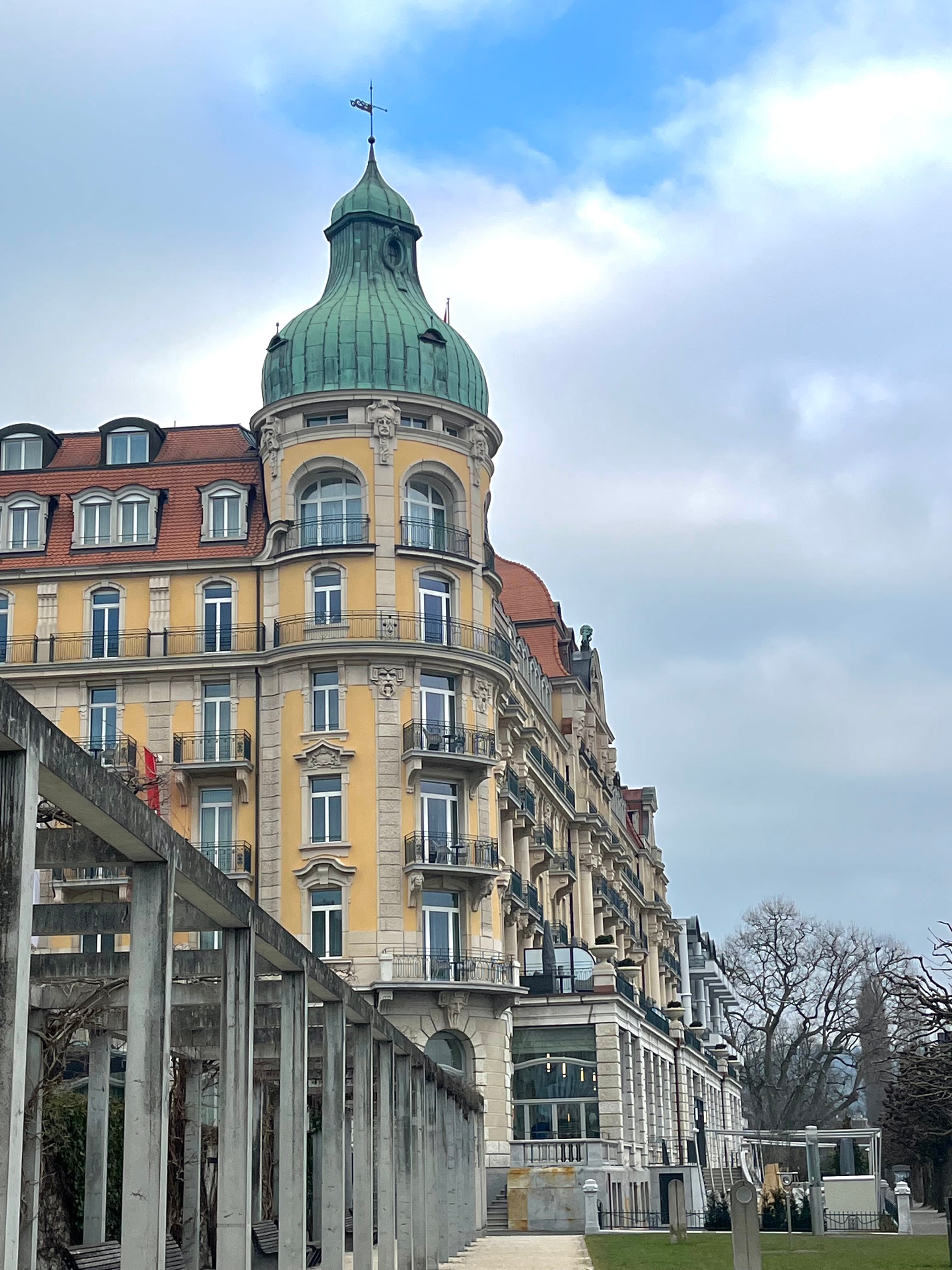 View of an old city building with windows and small balconies and a green domed roof at the corner