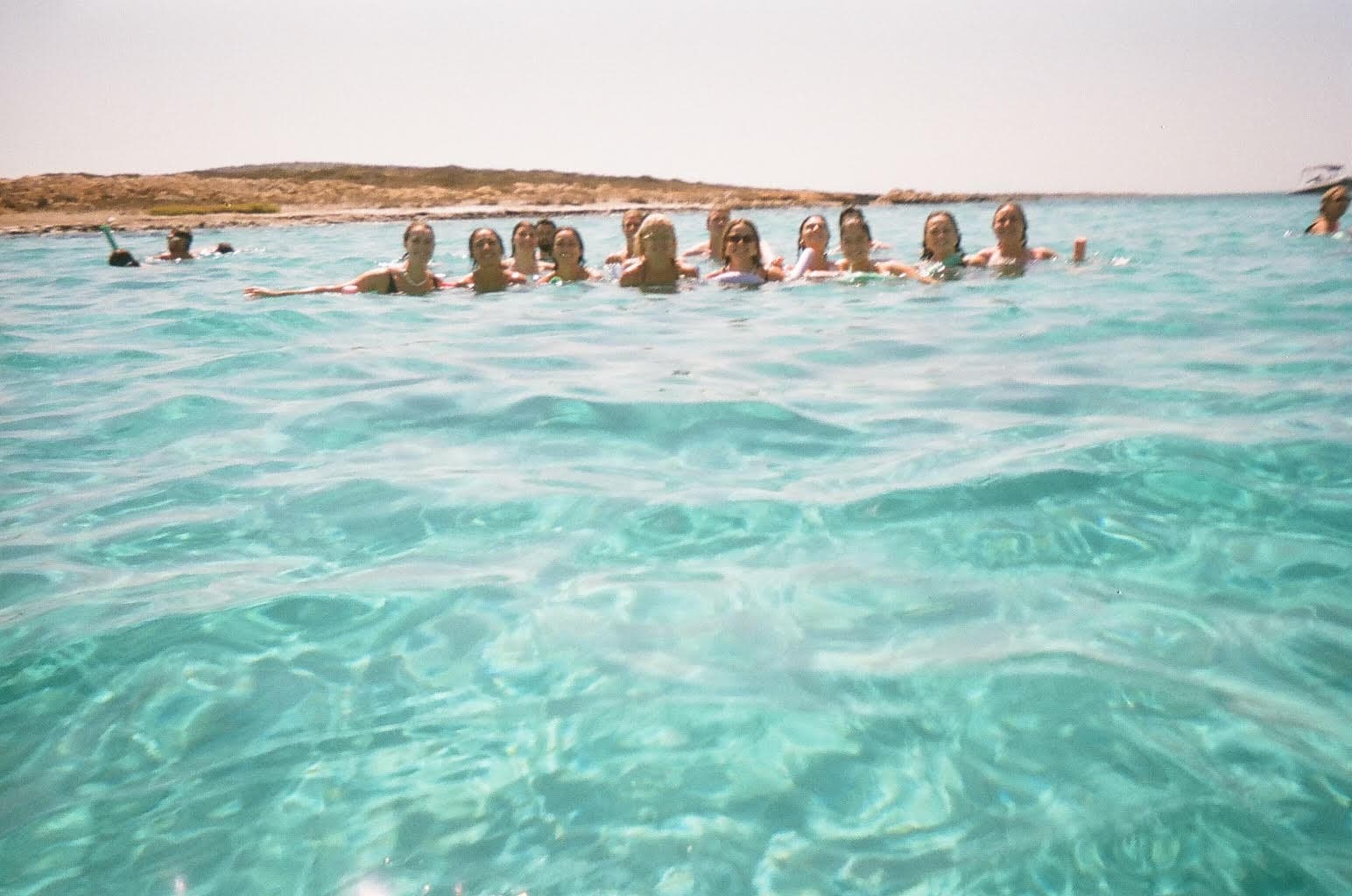 A group of women swimming together in a crystal clear ocean on a sunny day.