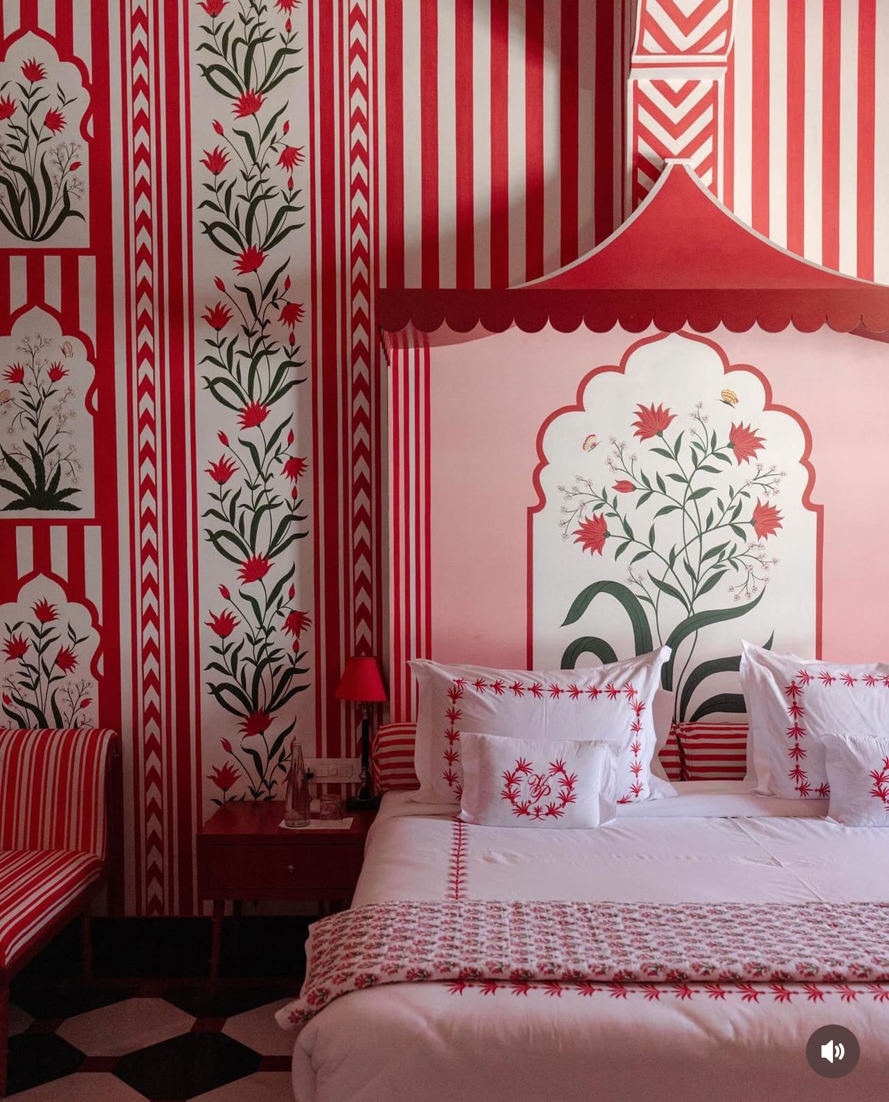 Interior view of a bedroom with vibrant red and white striped wallpaper and matching bed linens