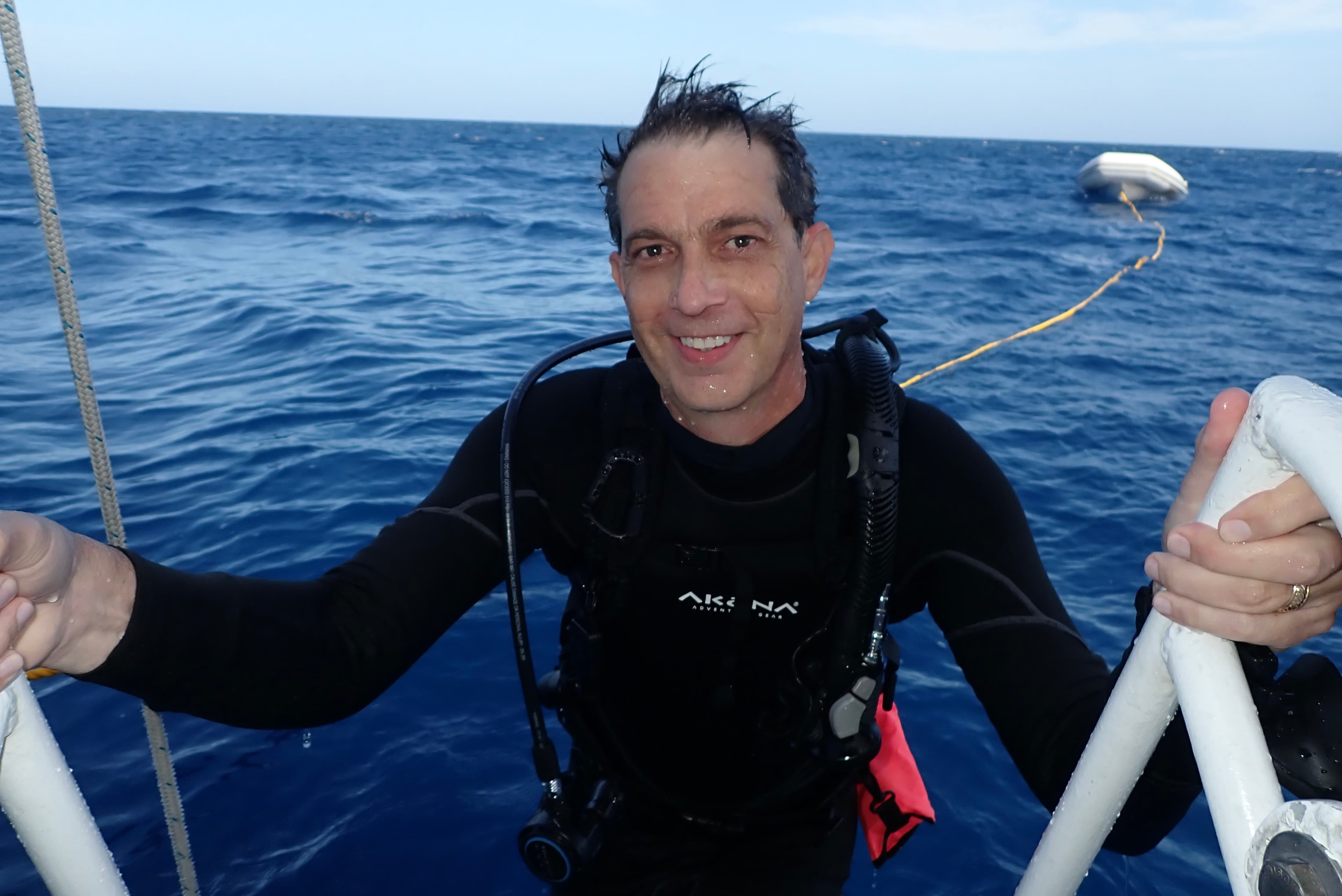 Advisor on the ladder of a boat at sea in scuba gear