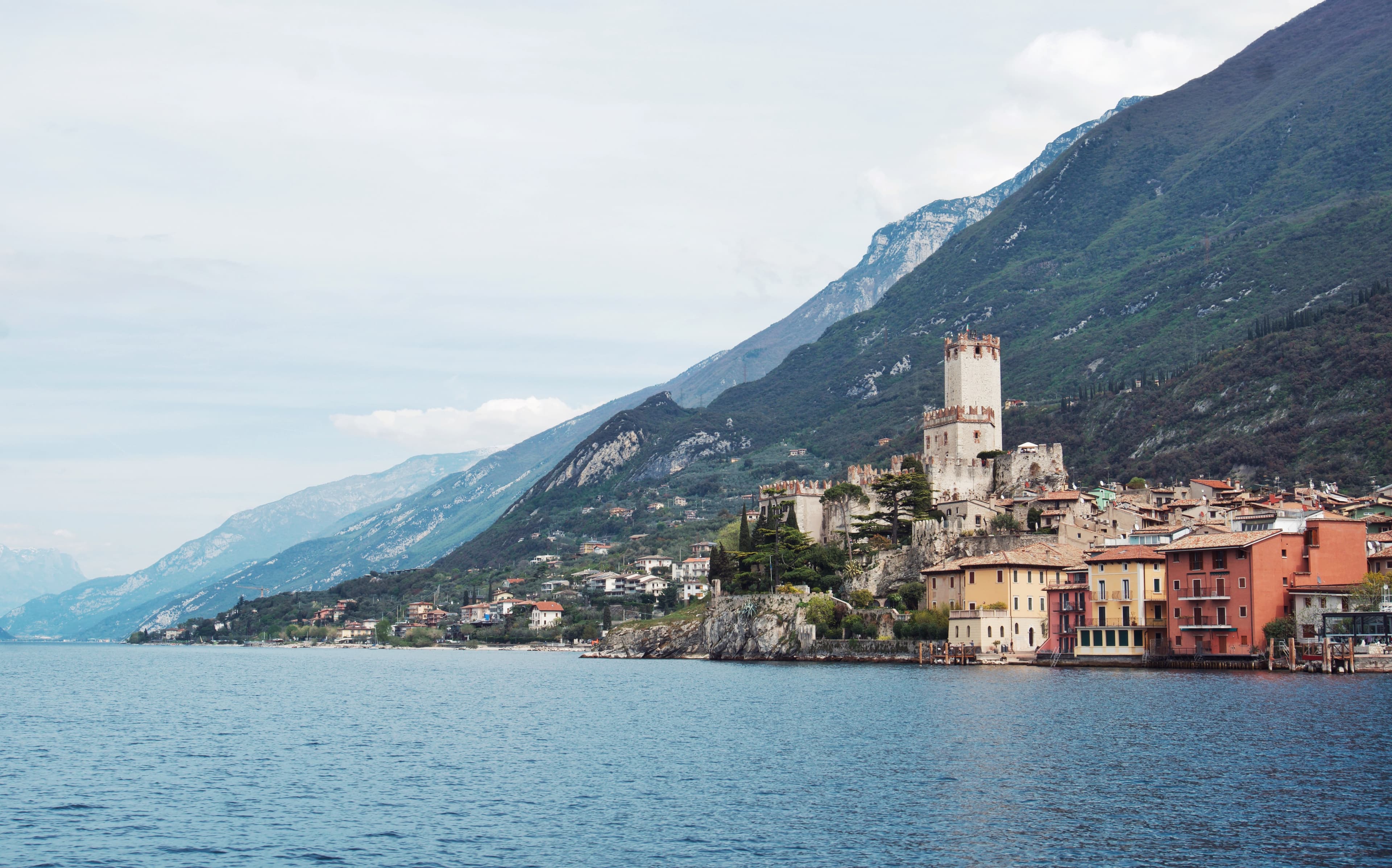 View of a beautiful waterfront town with mountains rising along the coast under cloudy skies
