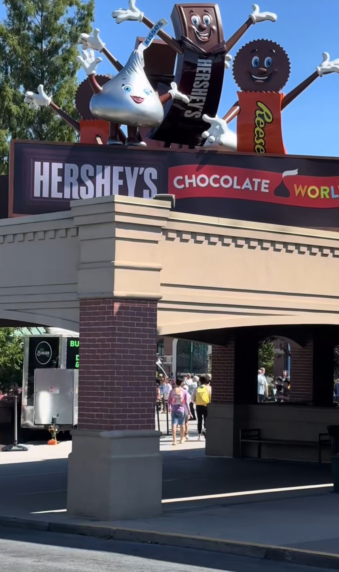 A picture of an entrance and the sign for "Hershey's Chocolate World" during the day.