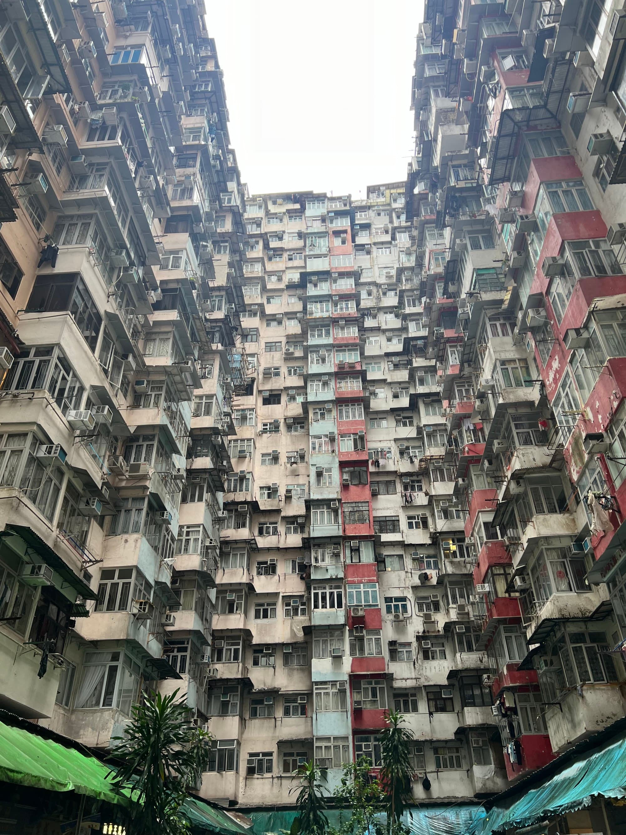 Looking up at a dense cluster of high-rise apartments with numerous air conditioning units on their exteriors.
