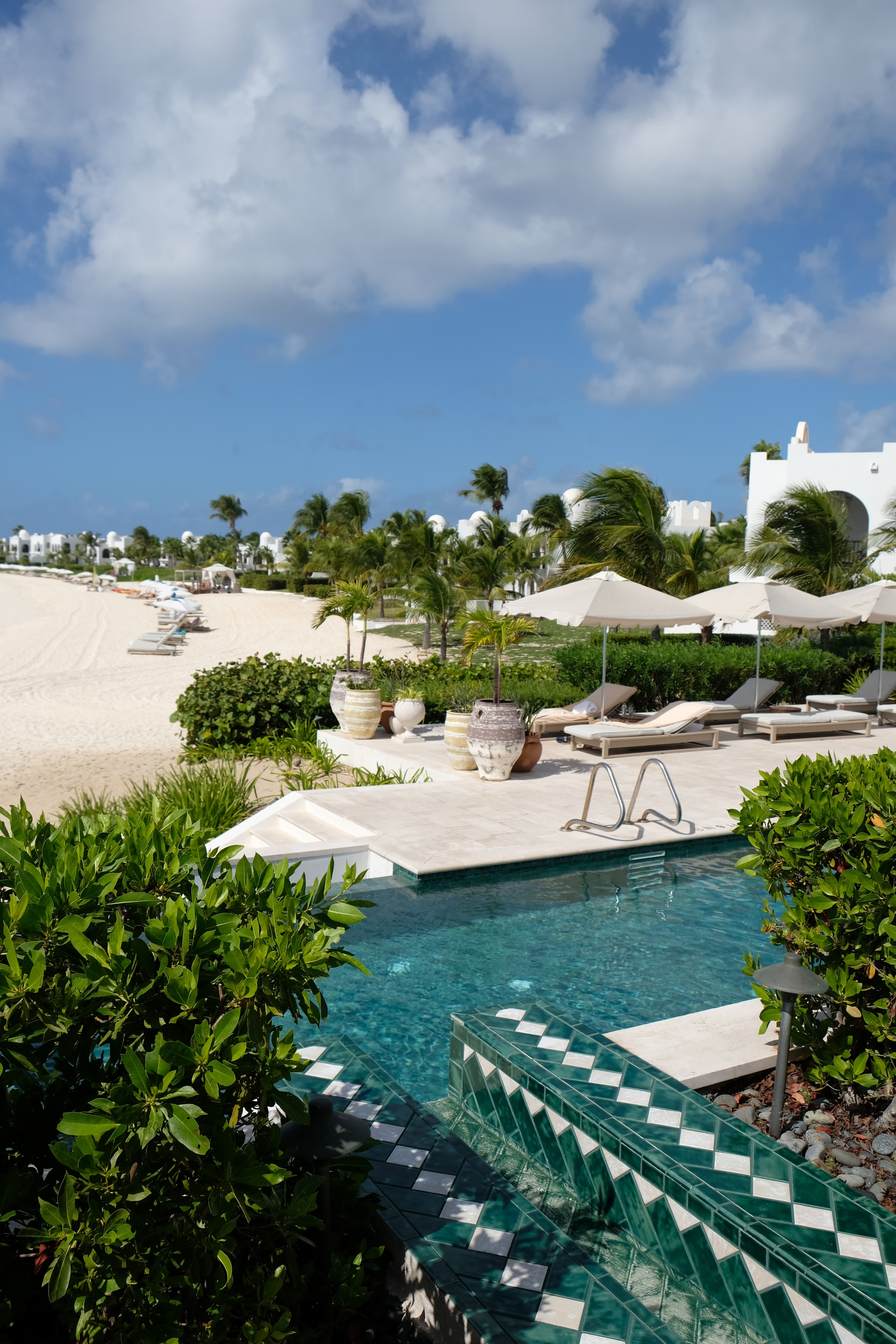 chairs next to pool with beach in the distance