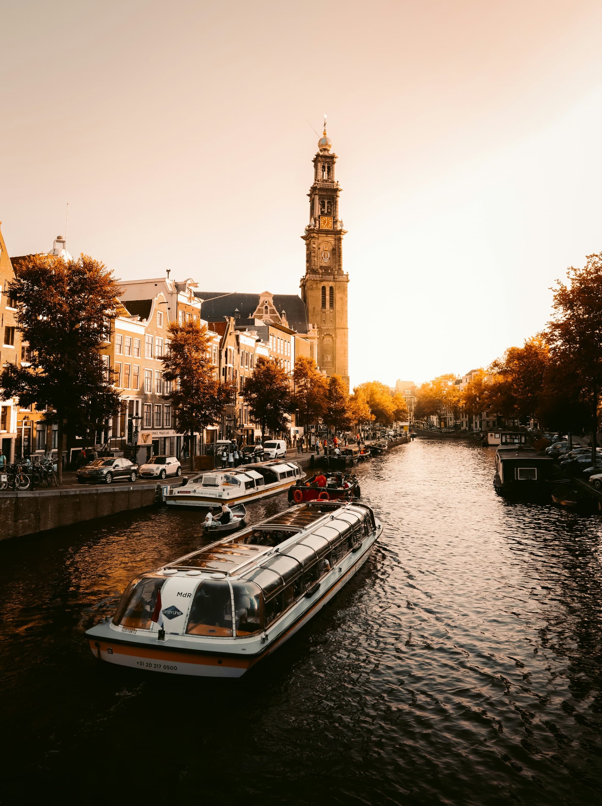 A scenic view of a canal with a boat, lined by historic buildings under a warm sunset light.