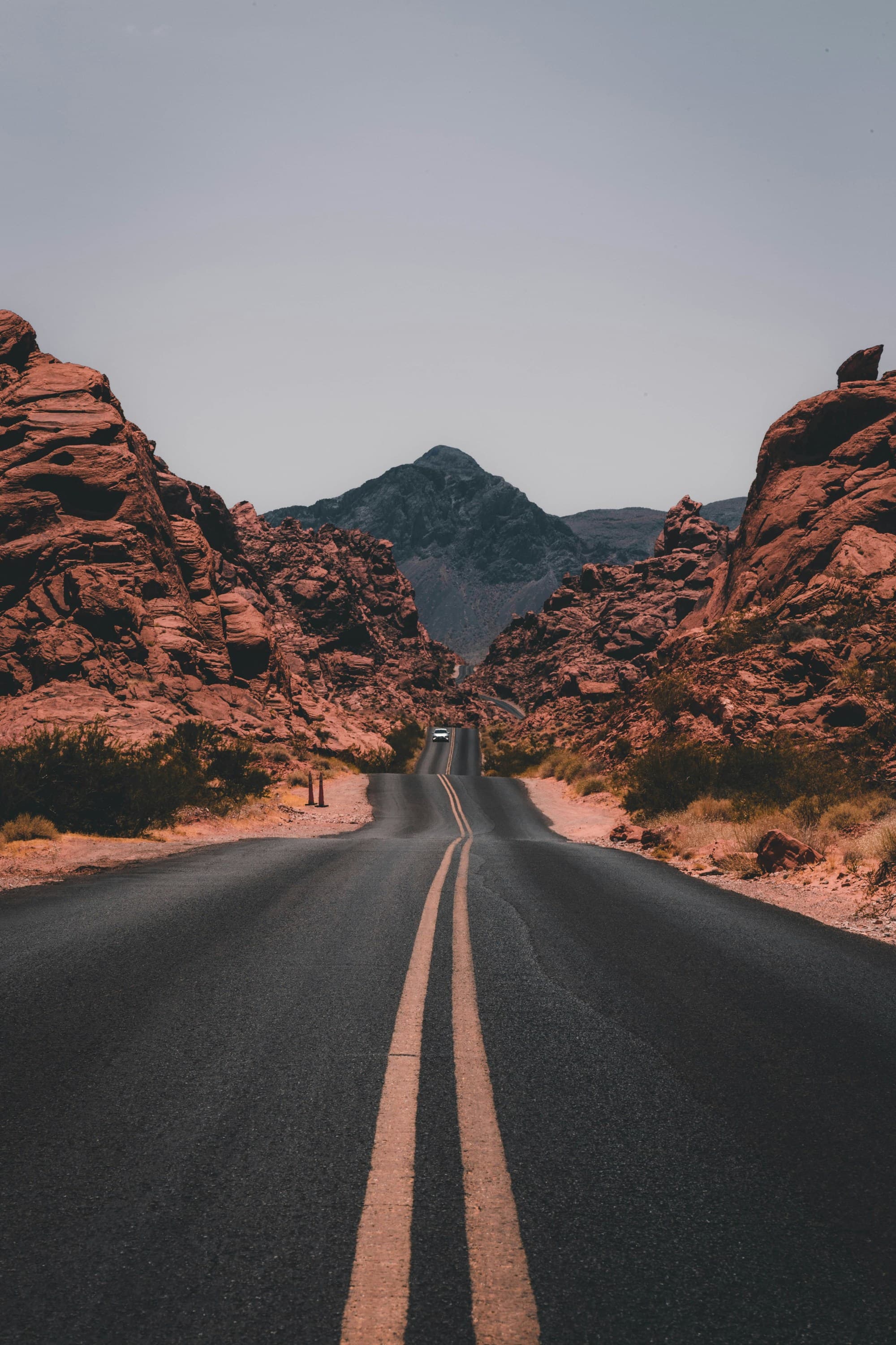 A road winds between rocky mountains that stretch to the horizon on a clear day.