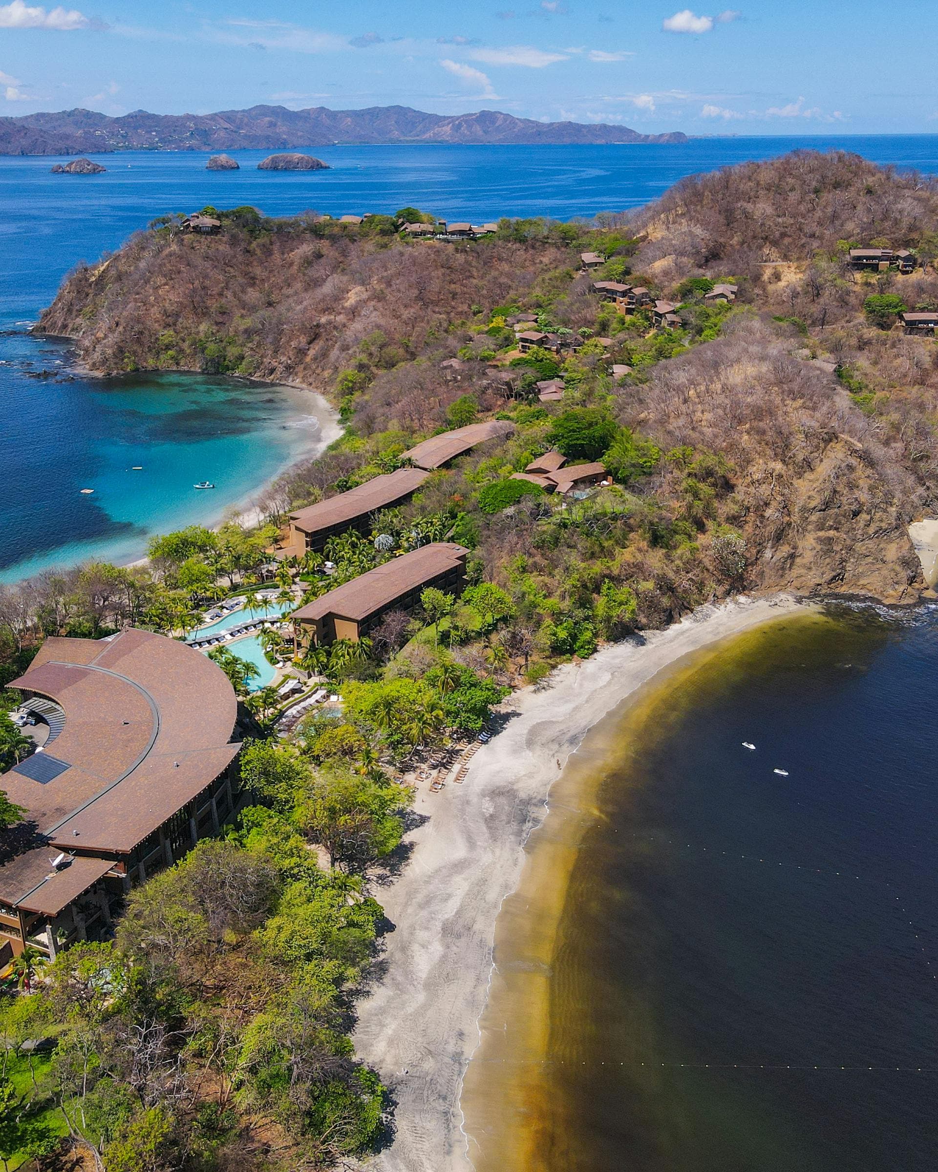 Four Season Resort in Costa Rica at Peninsula Papagayo stands against the crystal-clear water on a sunny day.