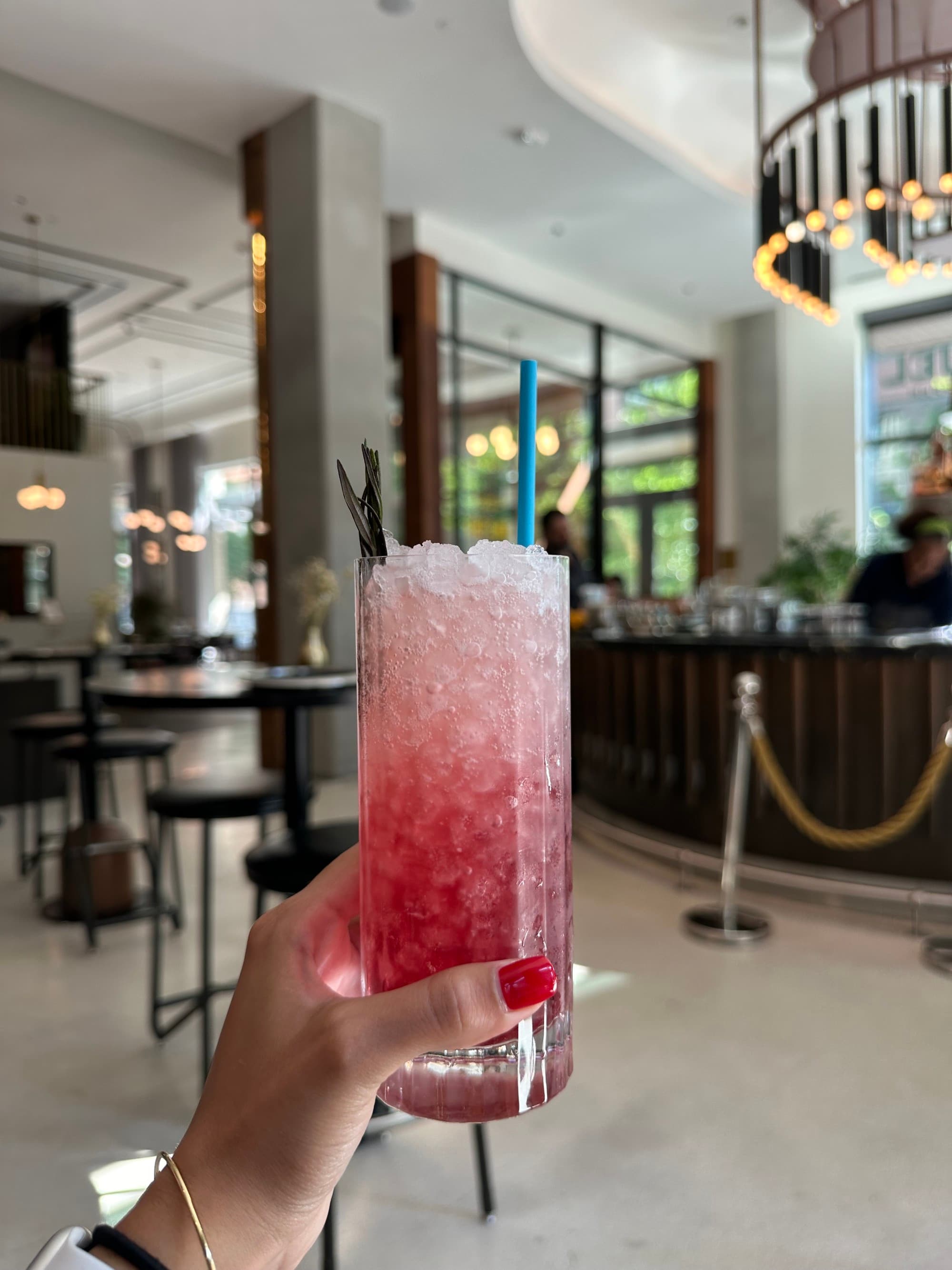 A pink drink in a tall glass with ice
