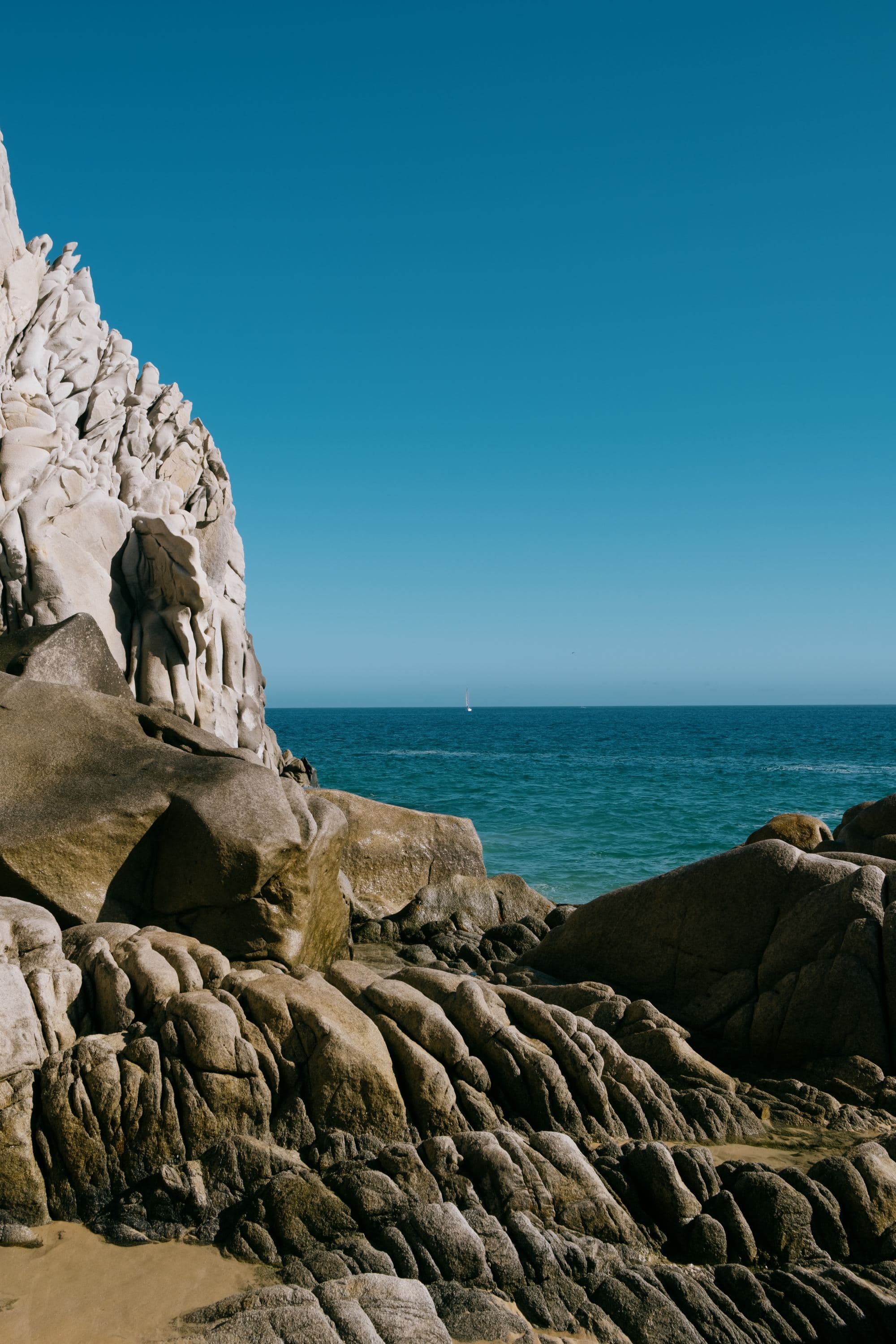 rocky shore of a beach with vibrant blue sky