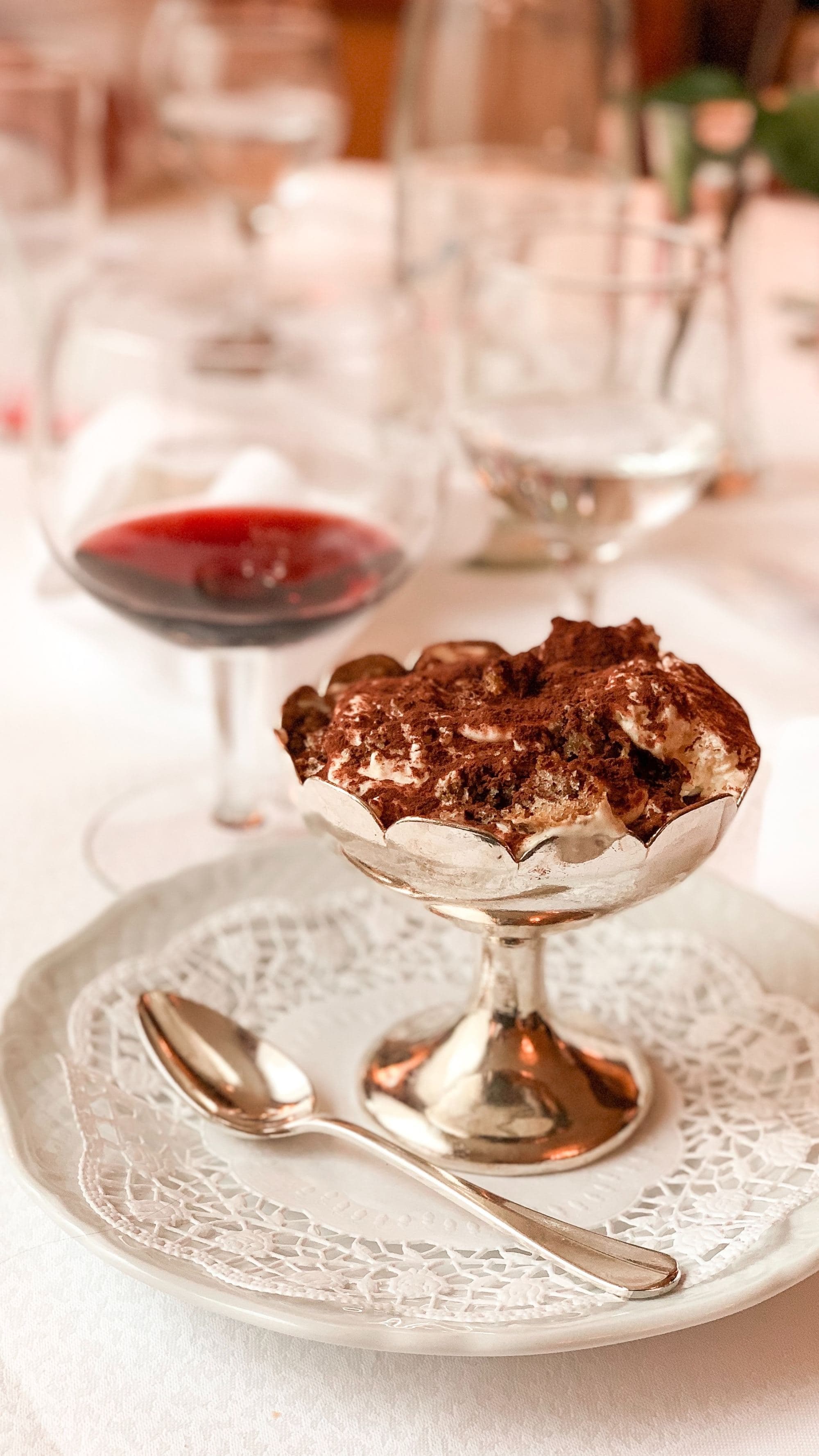 A picture of gold goblet filled dessert next to a wine glass.