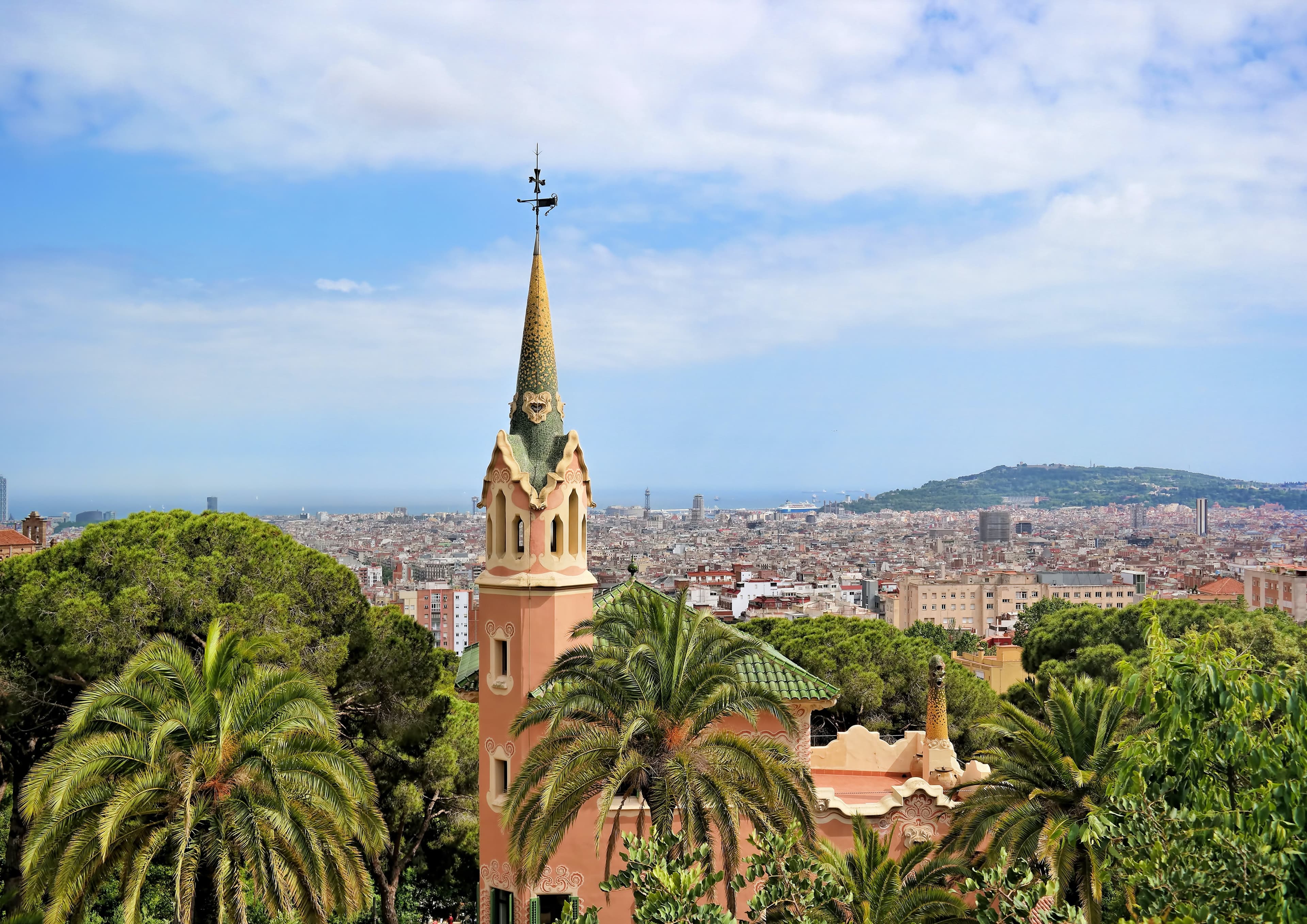 large steeple next to trees with city in background