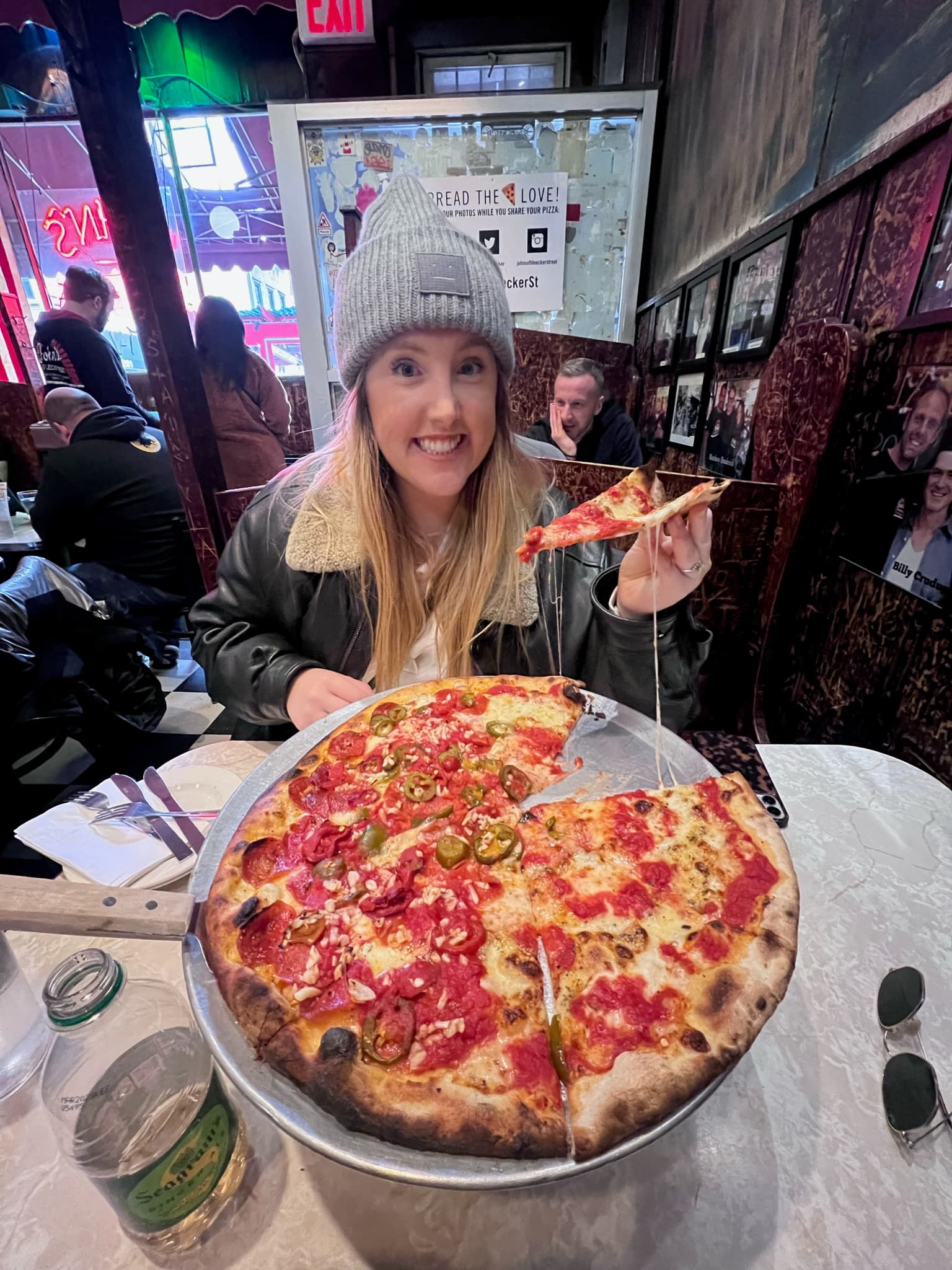 A woman getting a slice of pizza from the whole pizza.