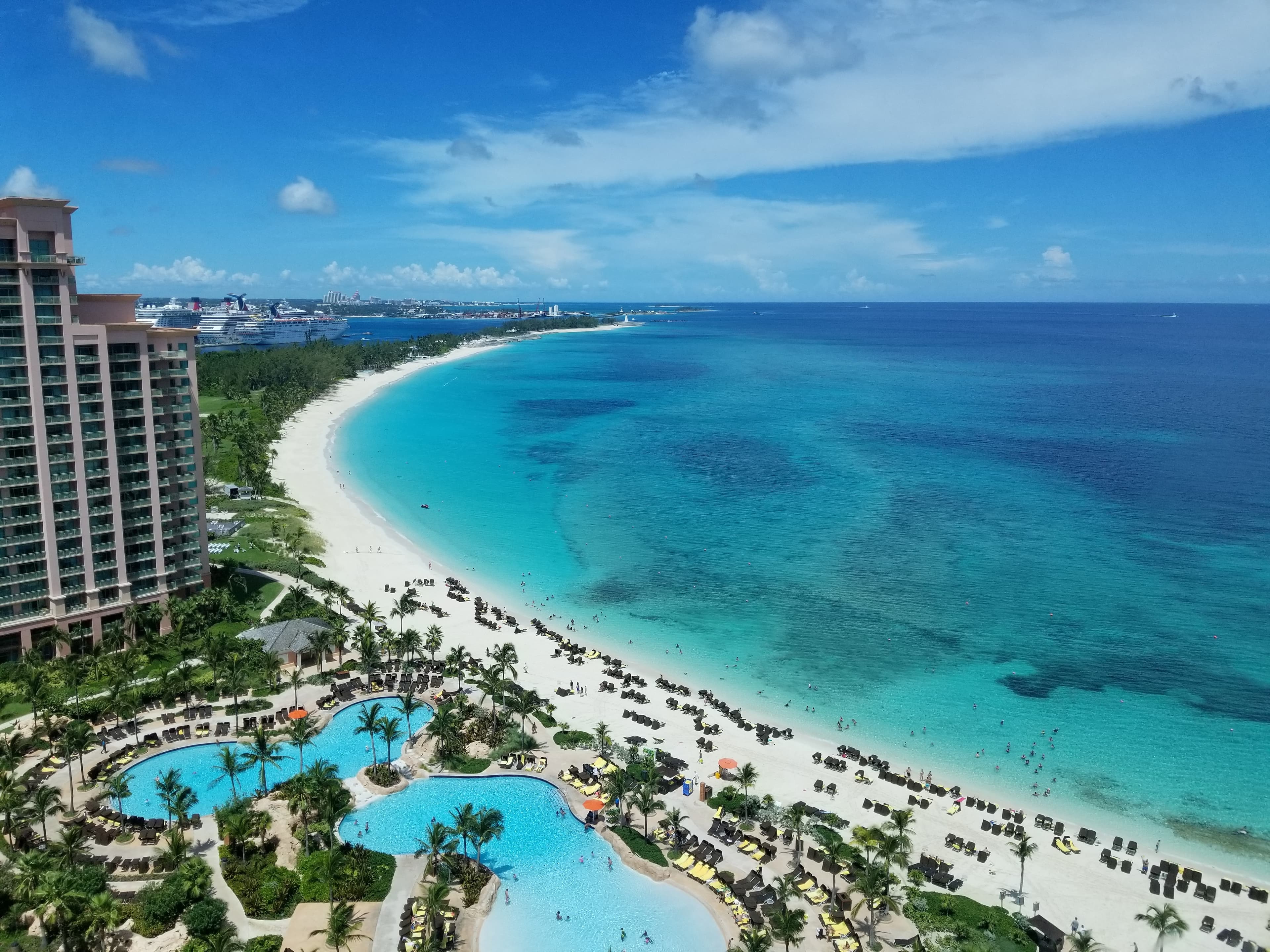 aerial view of blue ocean and white sand next to tall buildings