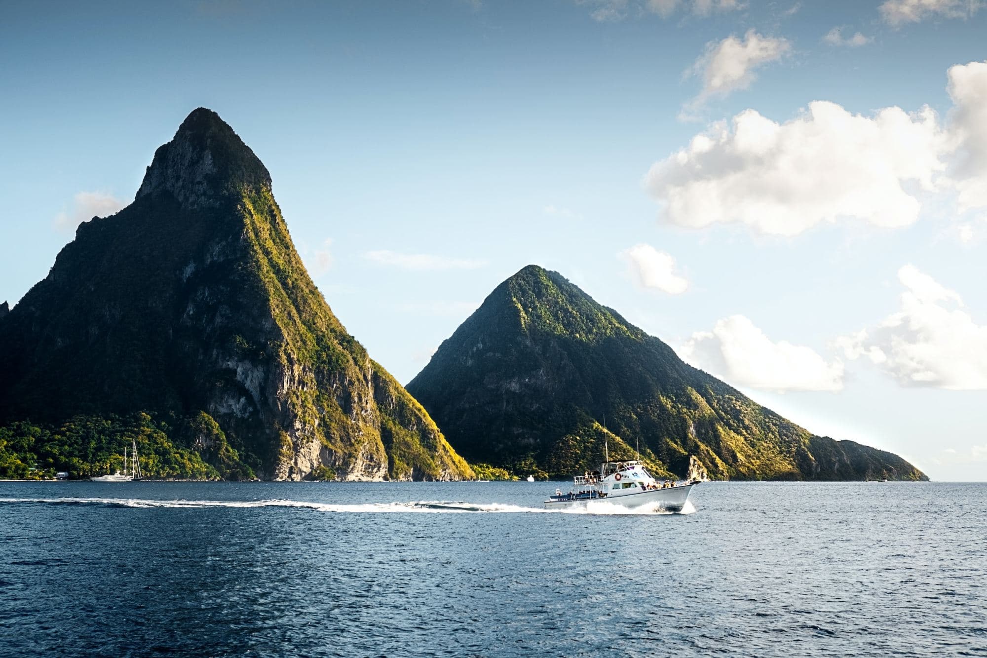 the twin volcanic peaks of Piton's Peak across the bay with a tour boat taking travelers around the island (photo by Daniel Öberg)