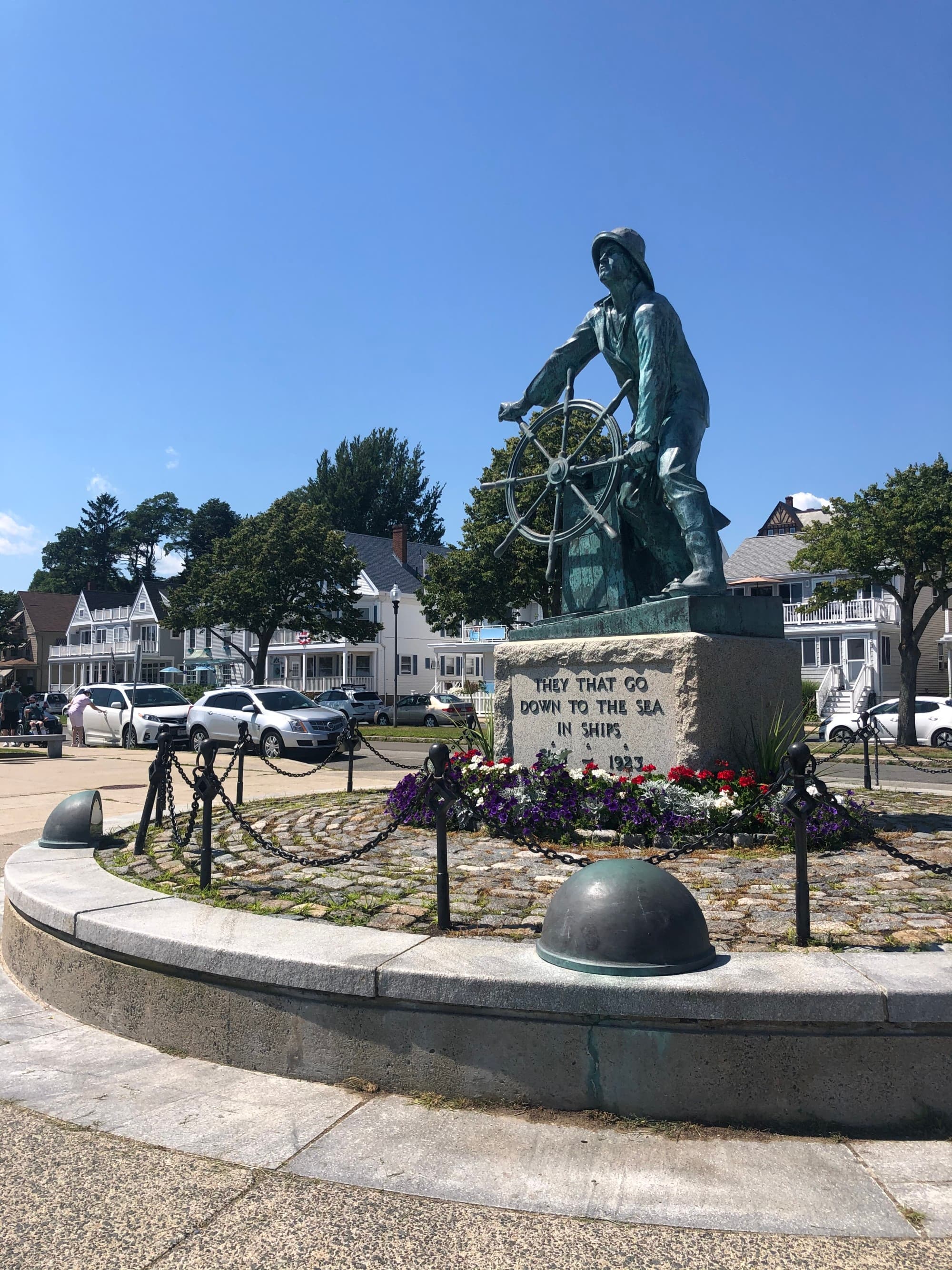 A statue of Nicolaus Copernicus with an armillary sphere, surrounded by flowers and benches in an outdoor setting.