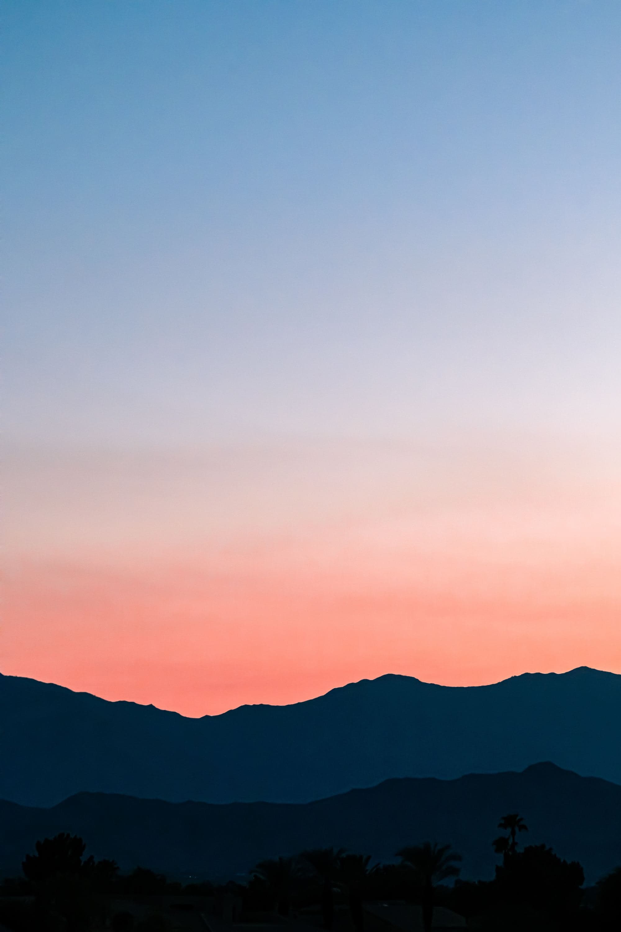 silhouette of a mountain range under a blue to pink sunset