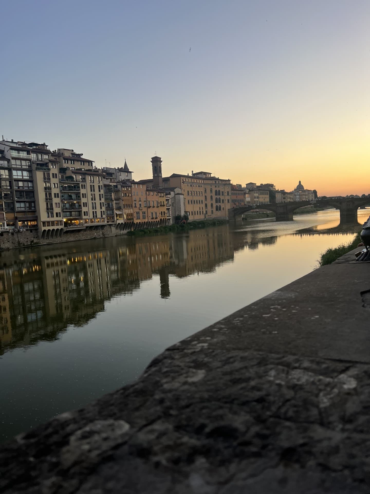 A canal of water in front of a row of buildings at nighttime