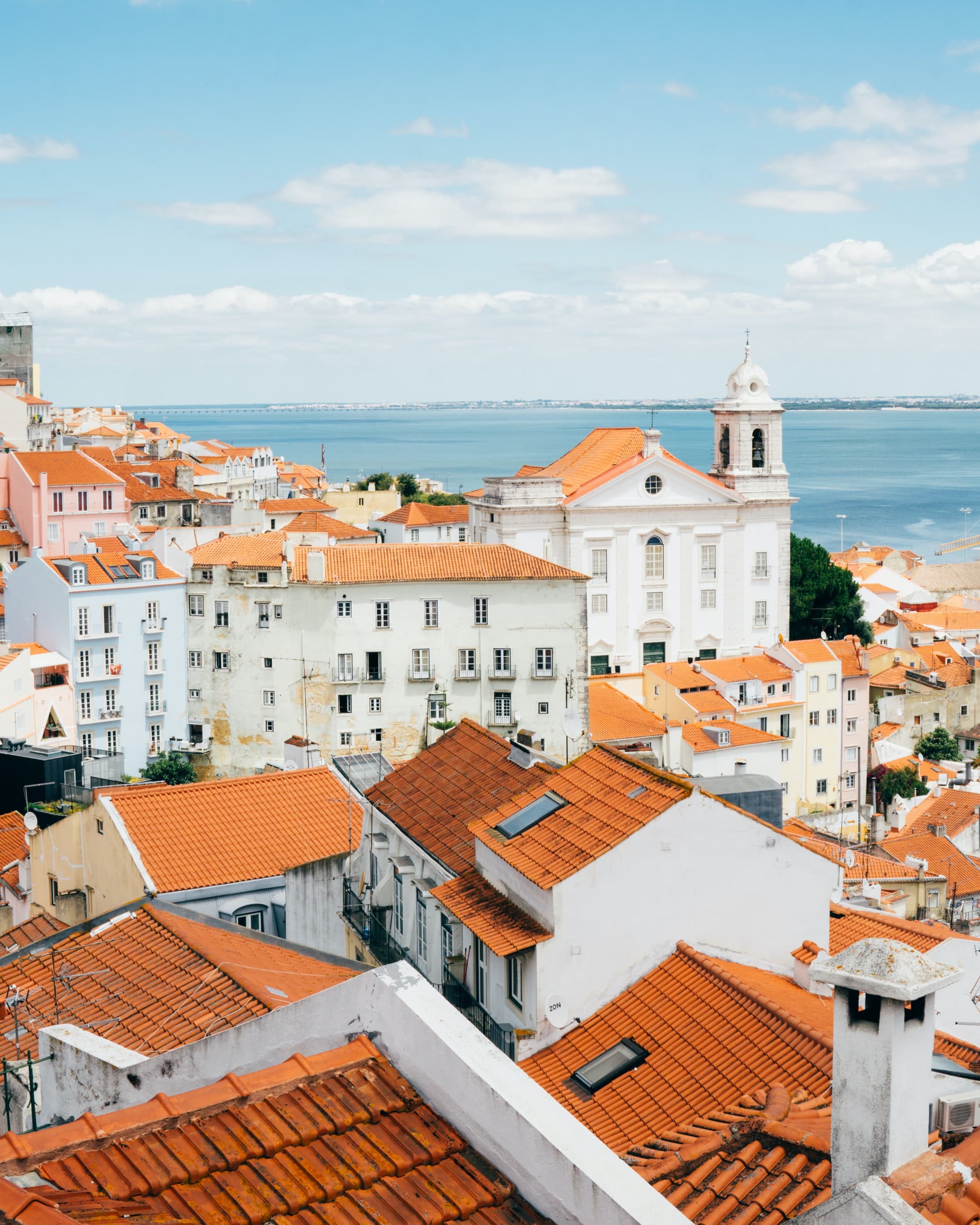 buildings with orange roofs next to body of water during daytime