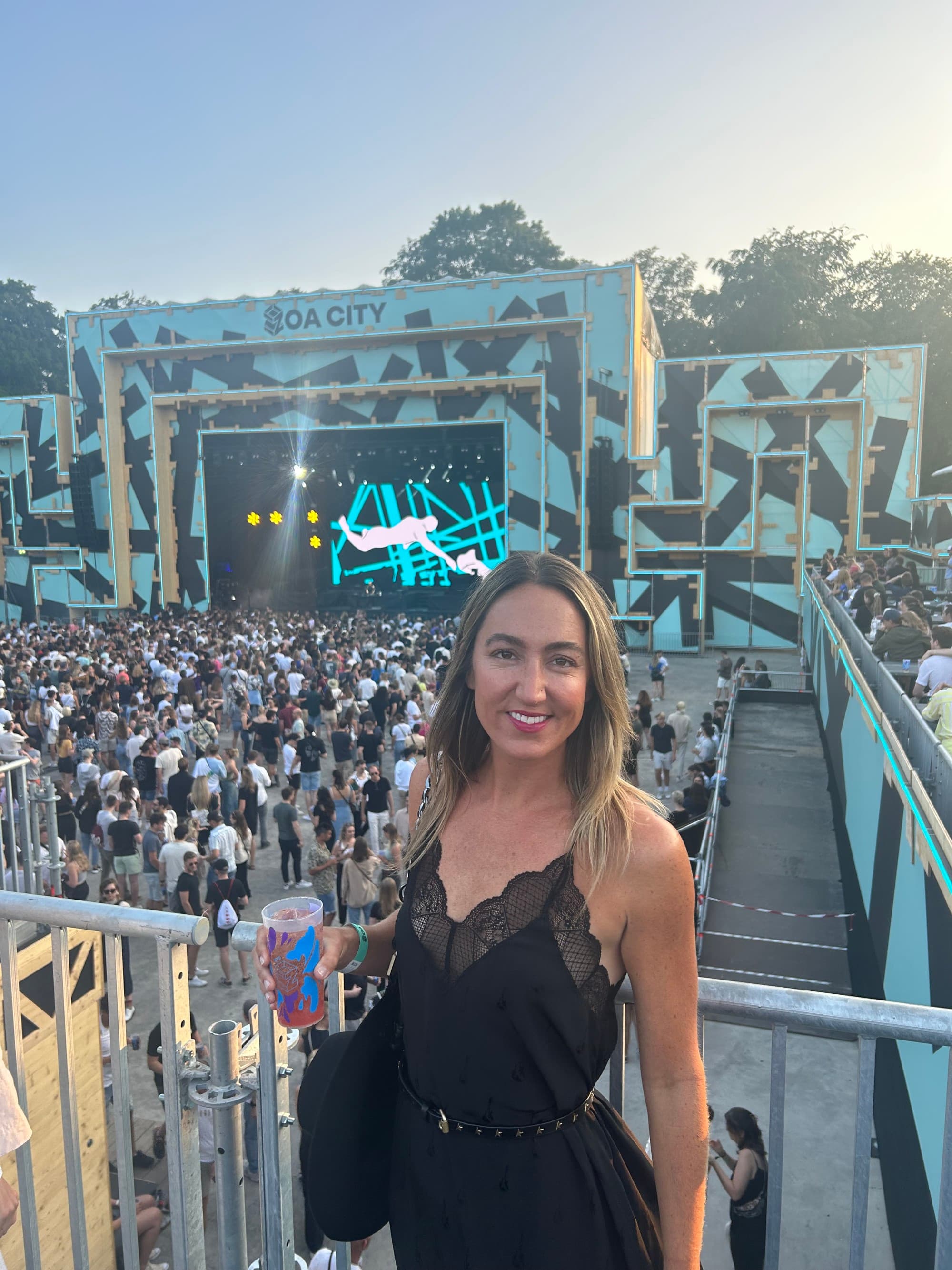 A woman in black dress with a concert crowd at the back.