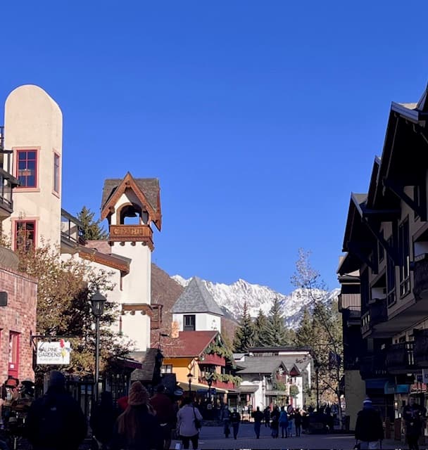 A street in Vail with a beautiful view and snow covered mountains in the distance.