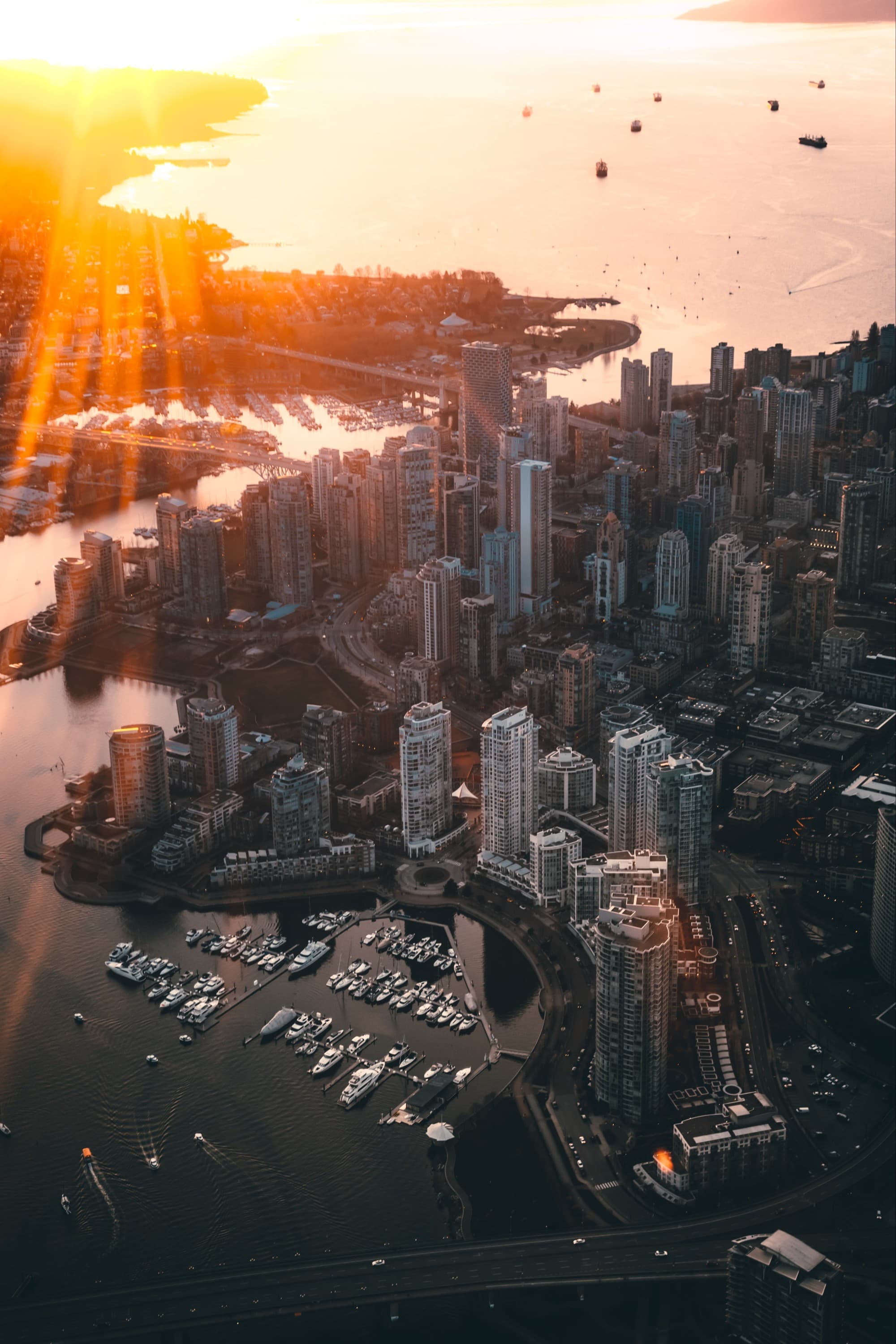 aerial view of a coastal big city at sunset with boats on the harbor