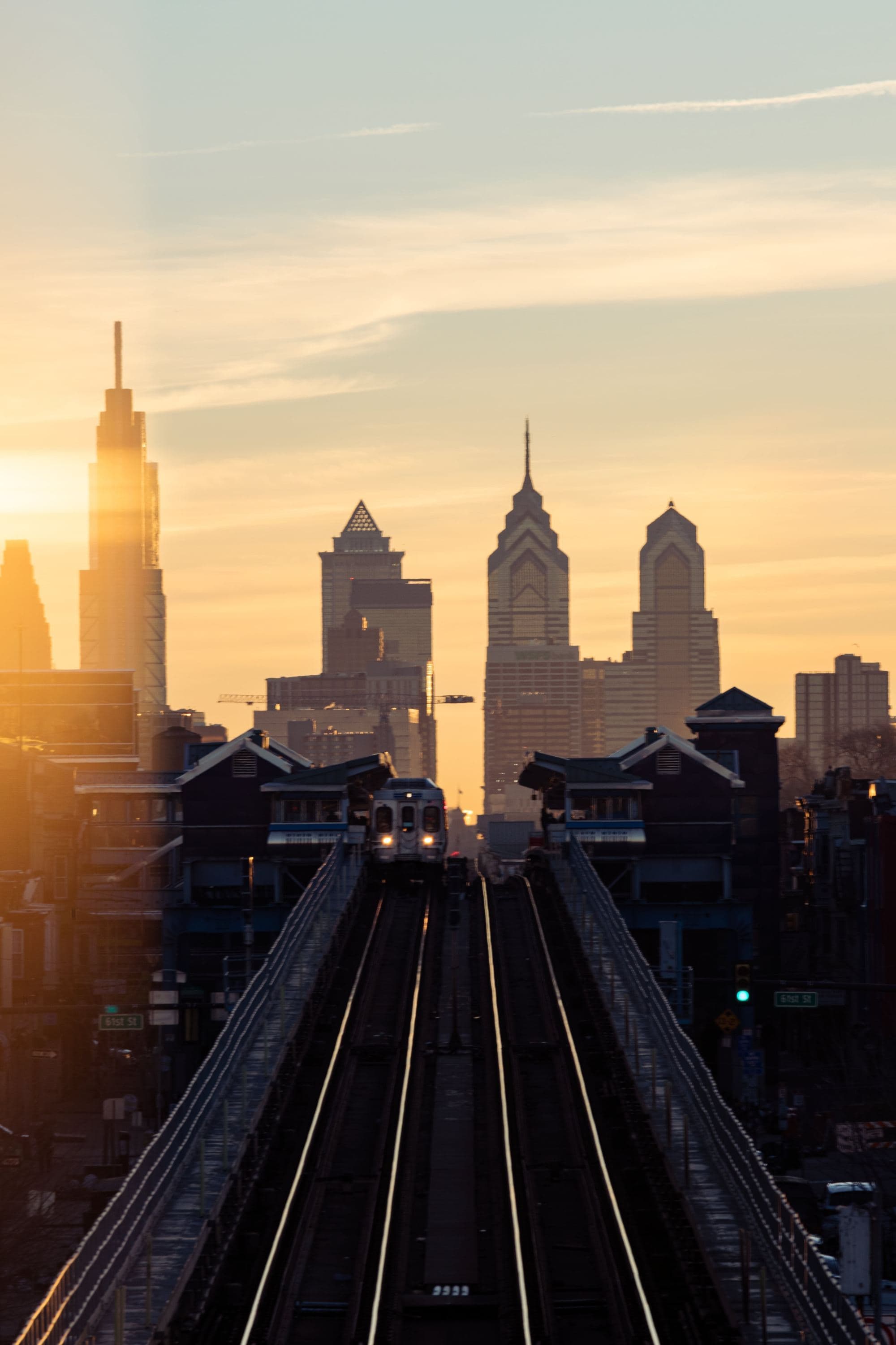 A train traveling over a bridge with a city in the background.