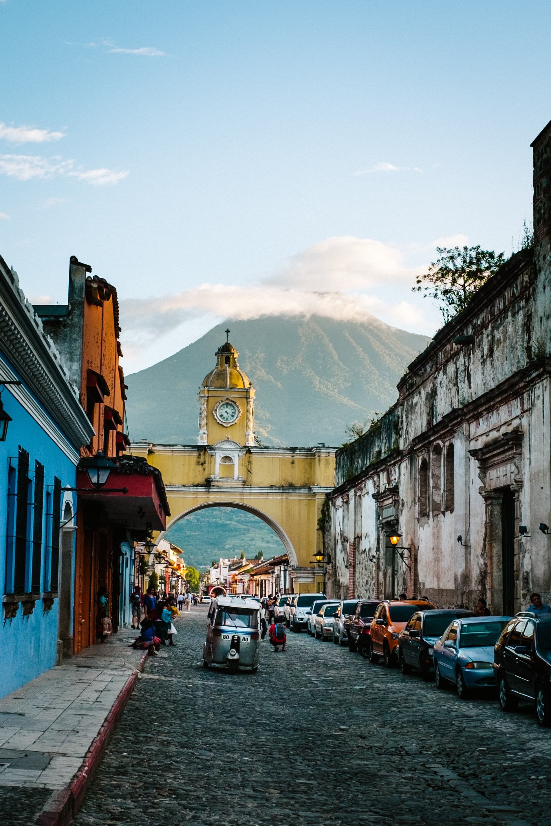 cobblestone street with arch tower and mountains