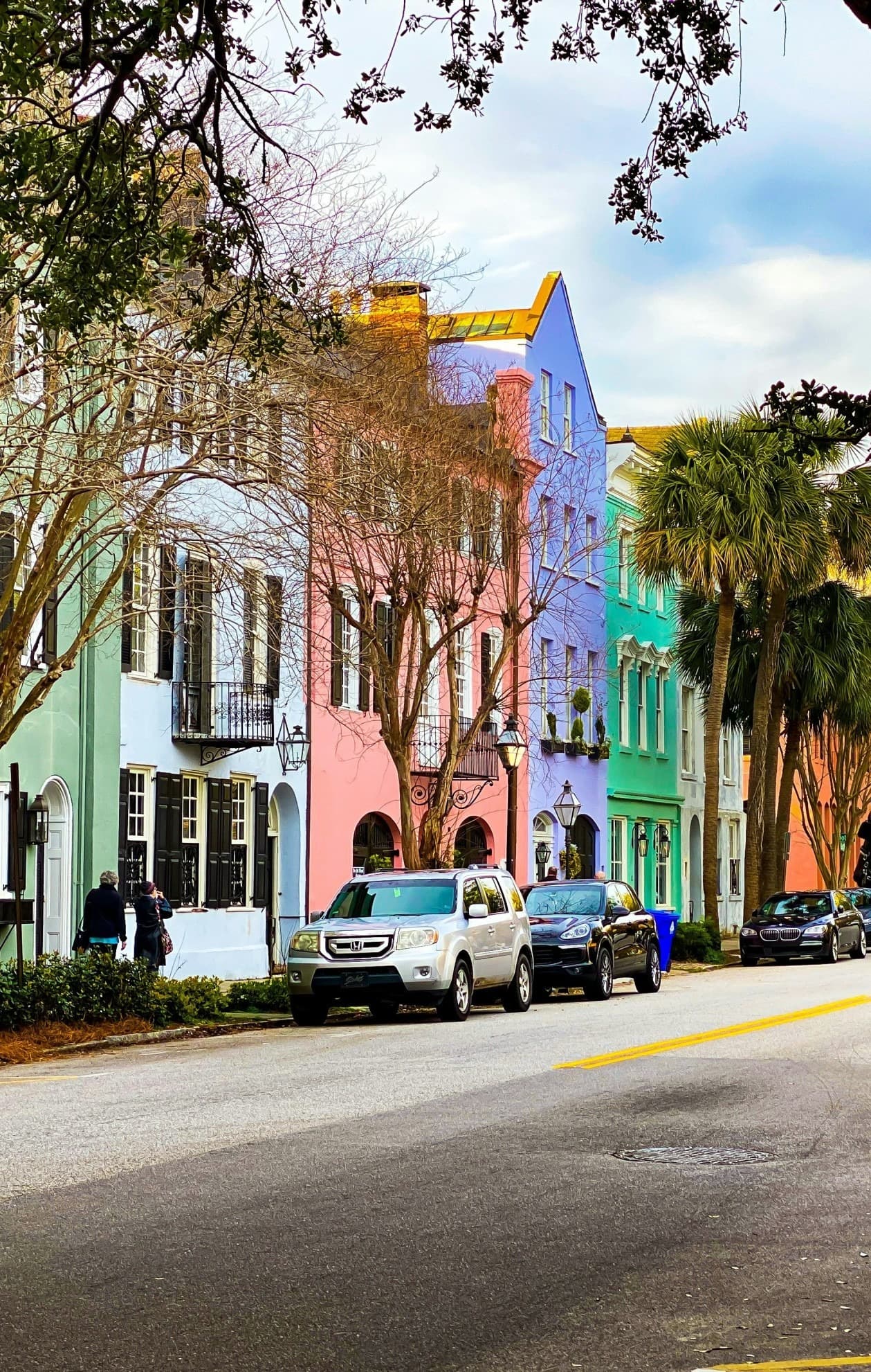 A view of colorful buildings, cars parked and trees.