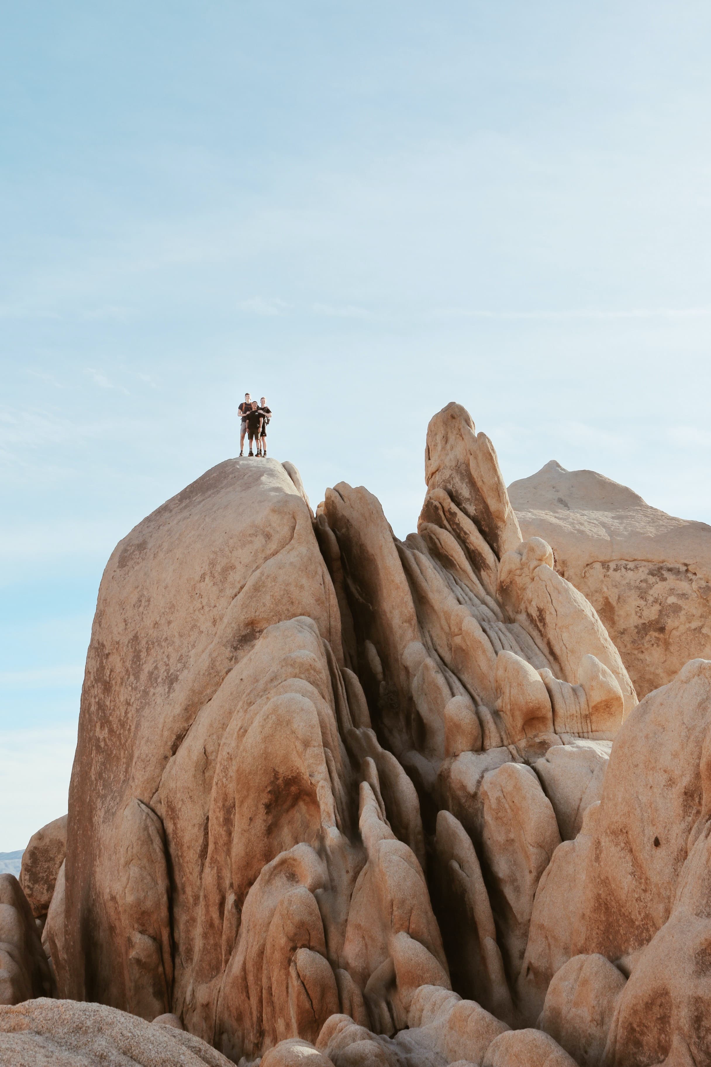 A family of three standing on a large rock in Joshua Tree.