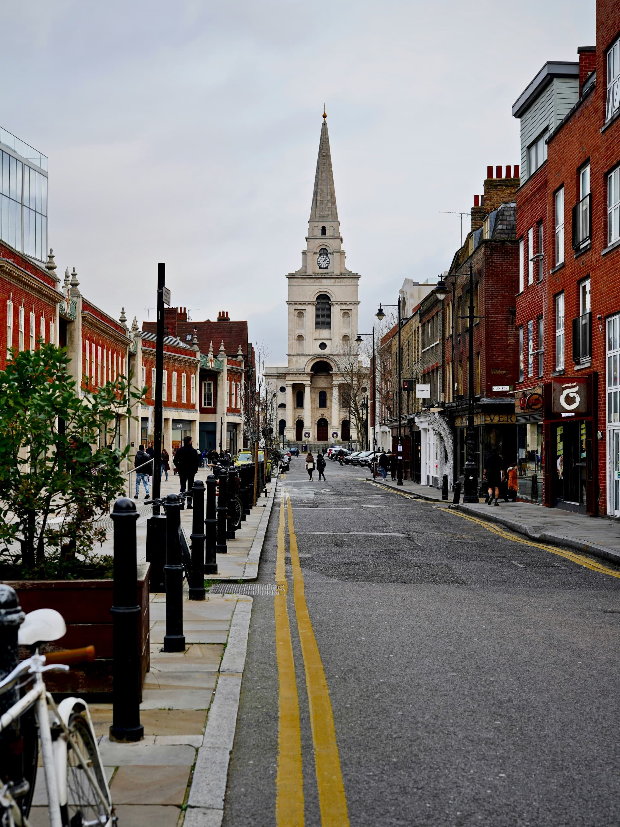 A street leading to a church with red brick buildings on sides.